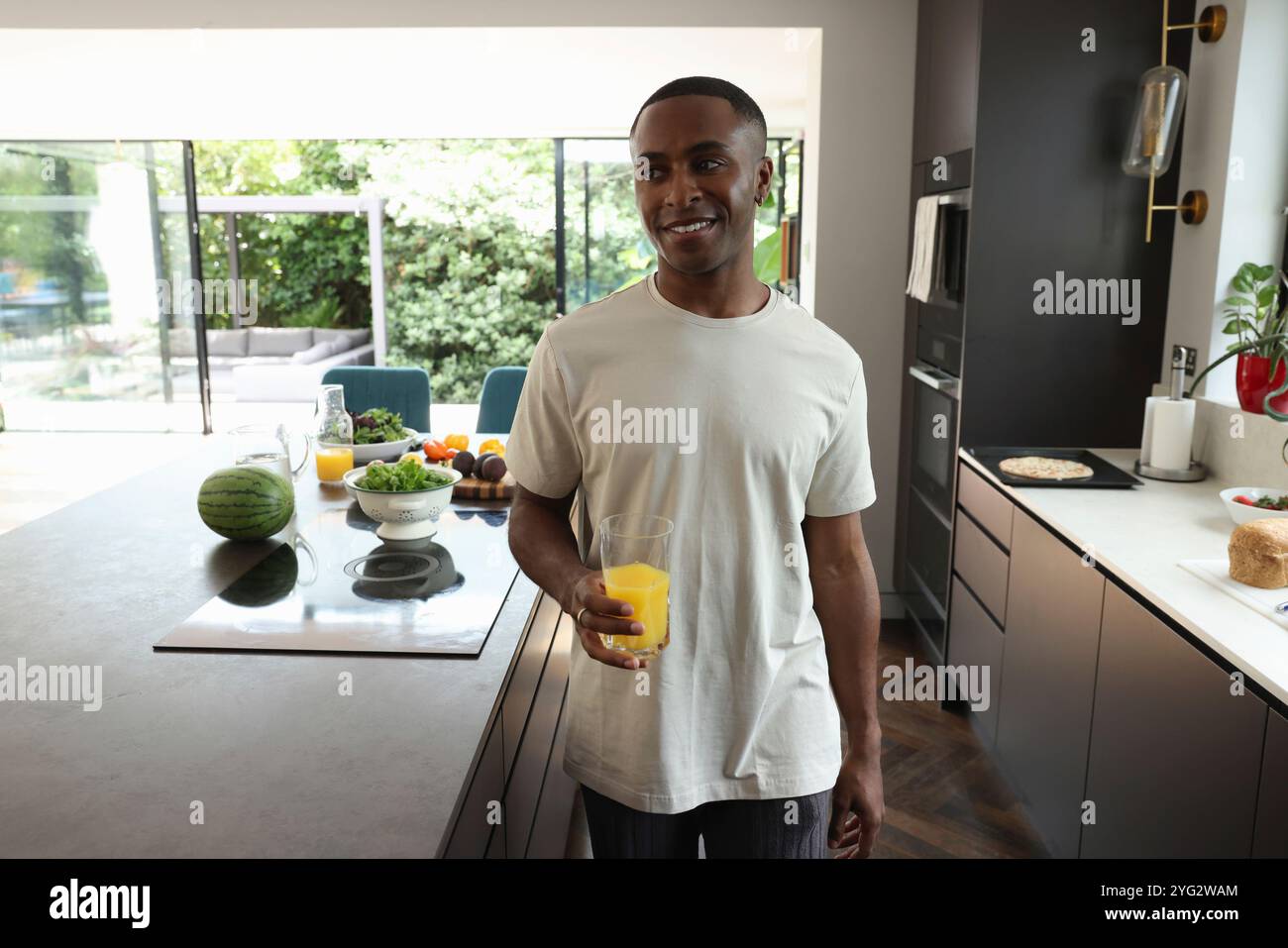 Uomo che tiene un bicchiere di succo d'arancia in cucina Foto Stock