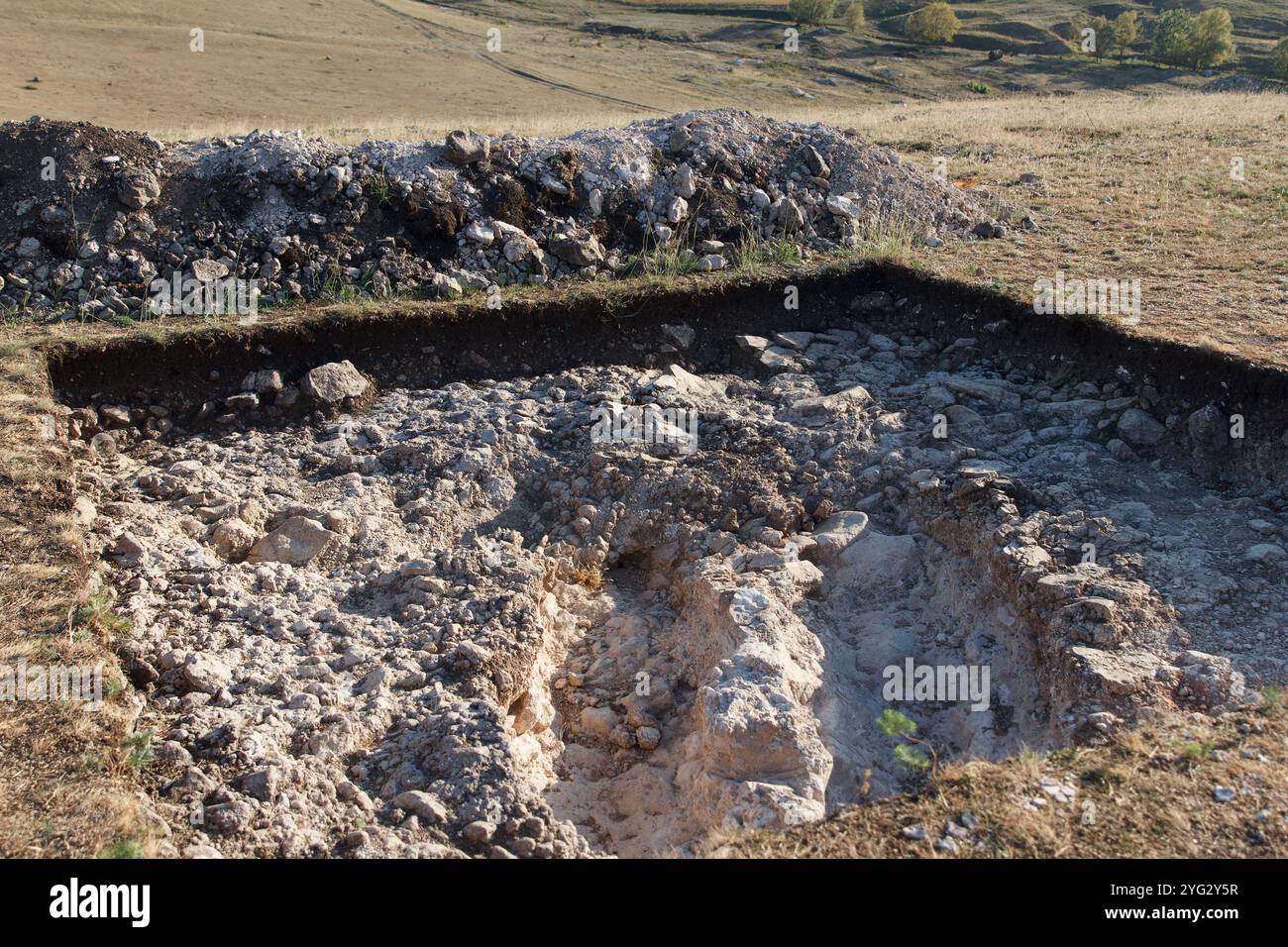 Fondo roccioso di una fossa archeologica scavata su una collina alla ricerca di manufatti storici. Lavori archeologici Foto Stock