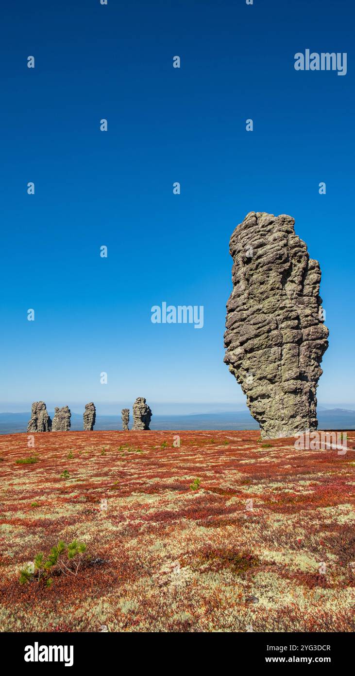 Vista mozzafiato delle formazioni rocciose manpupuner che torreggiano sul colorato paesaggio della tundra sotto un cielo azzurro cristallino nella repubblica komi, russia, creando una scena drammatica Foto Stock