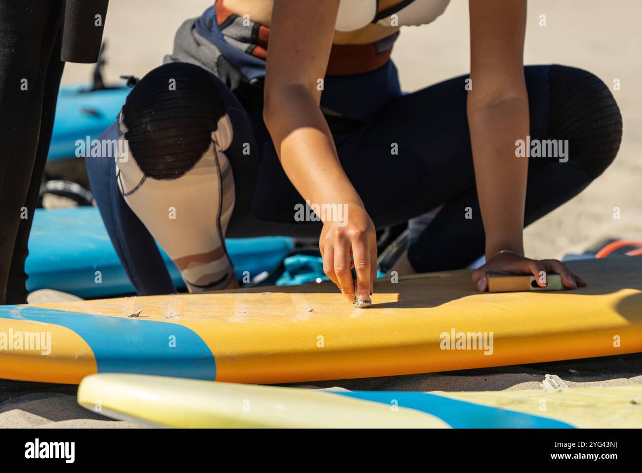 Cera da surf. Cerare una tavola da surf. La mano regge un pezzo di cera da surf e lubrifica la tavola da surf. Foto Stock