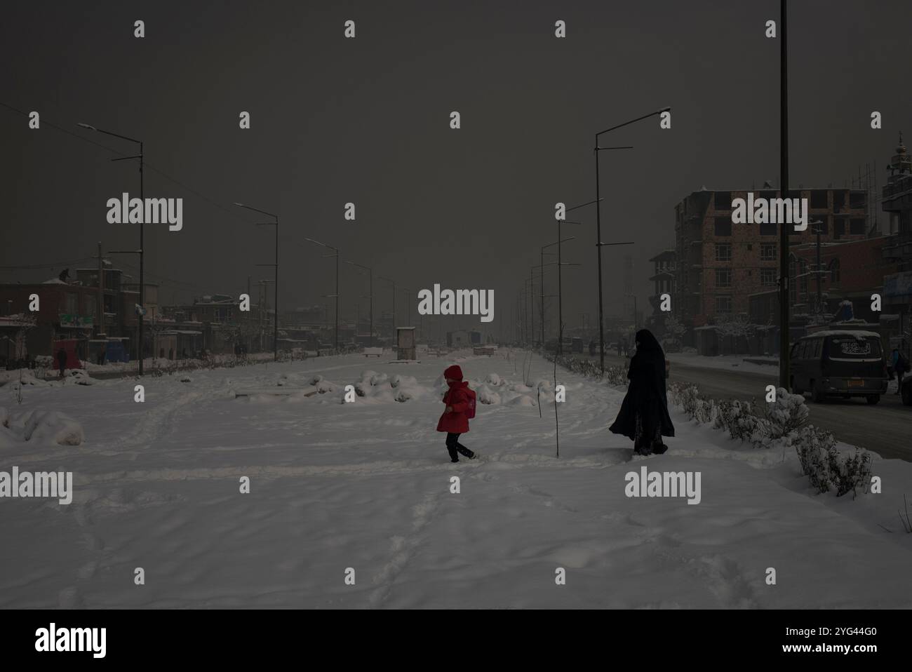 Una madre con sua figlia cammina attraverso un'area innevata della città durante una mattinata pesantemente inquinata a Kabul, Afghanistan, 4 febbraio 2020. Il Foto Stock