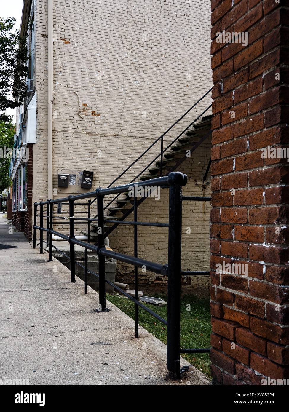 Una robusta porta di sicurezza nera dal design ornamentale, incorniciata da un muro di mattoni testurizzati in un quartiere urbano durante il giorno Foto Stock