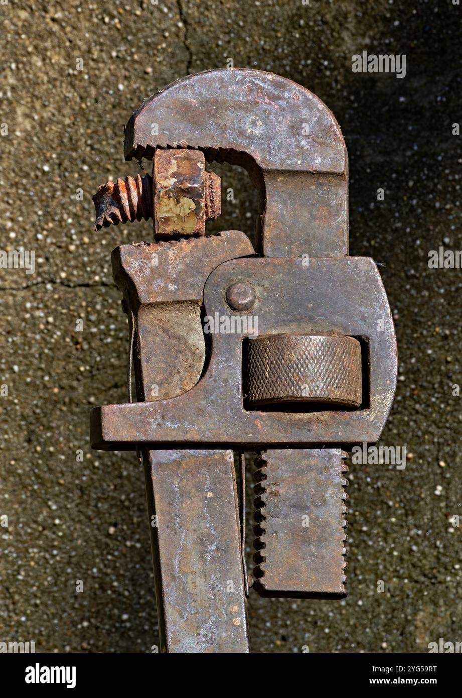 Primo piano di una chiave per tubi per idraulici Old Rusty Vintage. Su uno sfondo cementato. Con un bullone rotto nei denti. Foto Stock