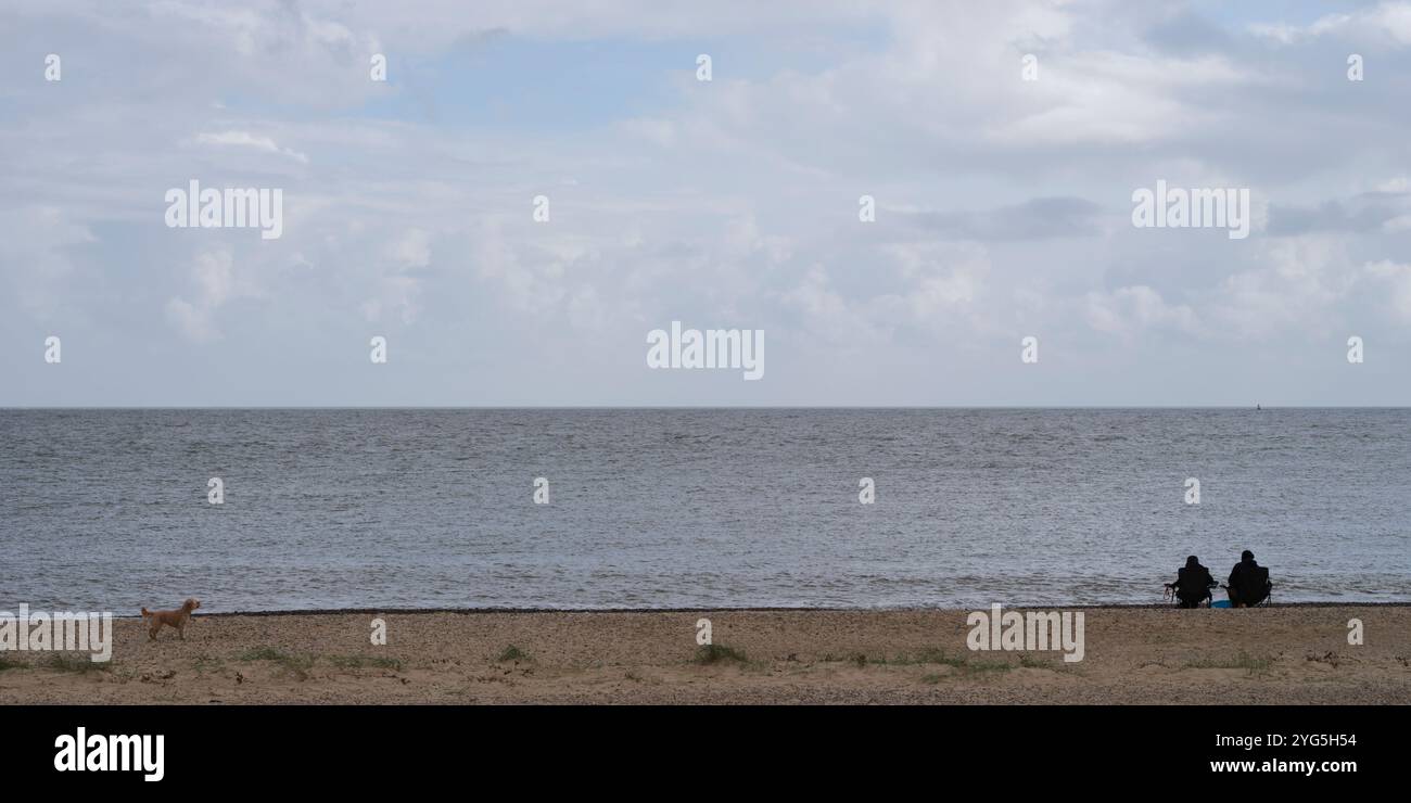 Un solo cane e una coppia seduti sulla spiaggia di Great Yarmouth, Norfolk Foto Stock
