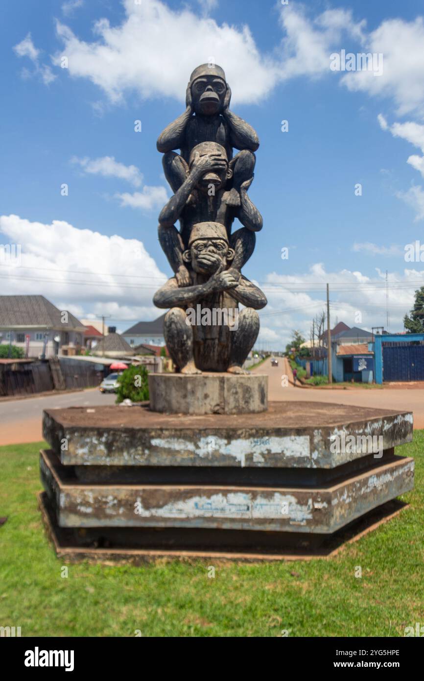 Statua delle tre scimmie sagge in una rotatoria di Enugu, Nigeria, che simboleggia "Vedi il male, ascolta il male, parla il male" con un cielo blu e uno sfondo urbano Foto Stock