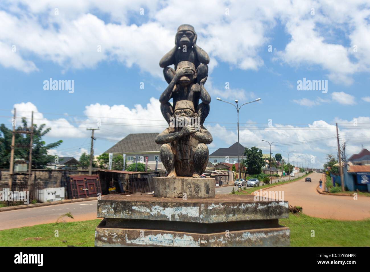 Statua delle tre scimmie sagge in una rotatoria di Enugu, Nigeria, che simboleggia "Vedi il male, ascolta il male, parla il male" con un cielo blu e uno sfondo urbano Foto Stock