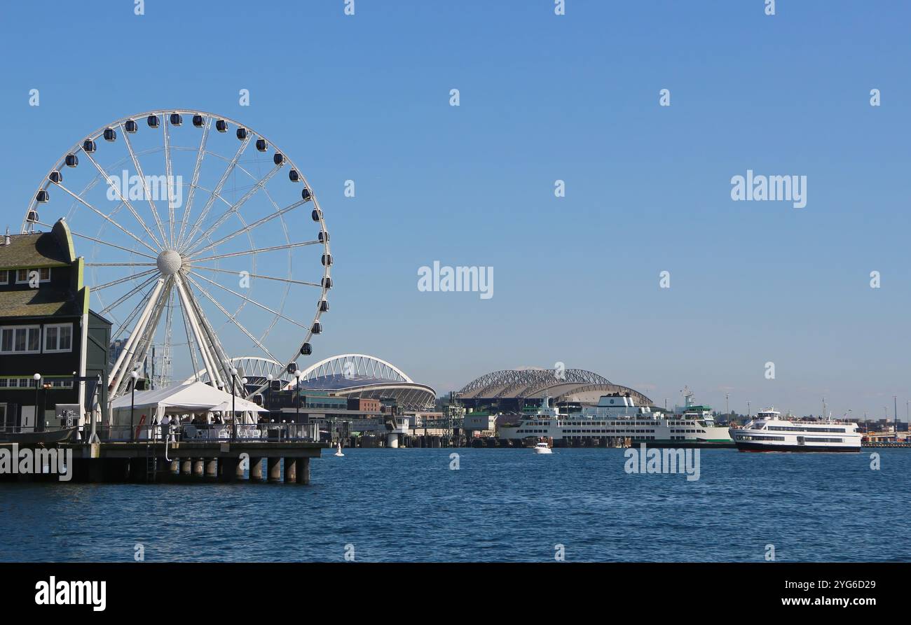 Vista sul mare con lo stadio Lumen Field e il T-Mobile Park in lontananza dal lungomare, con una grande ruota panoramica Seattle, Washington State USA Foto Stock