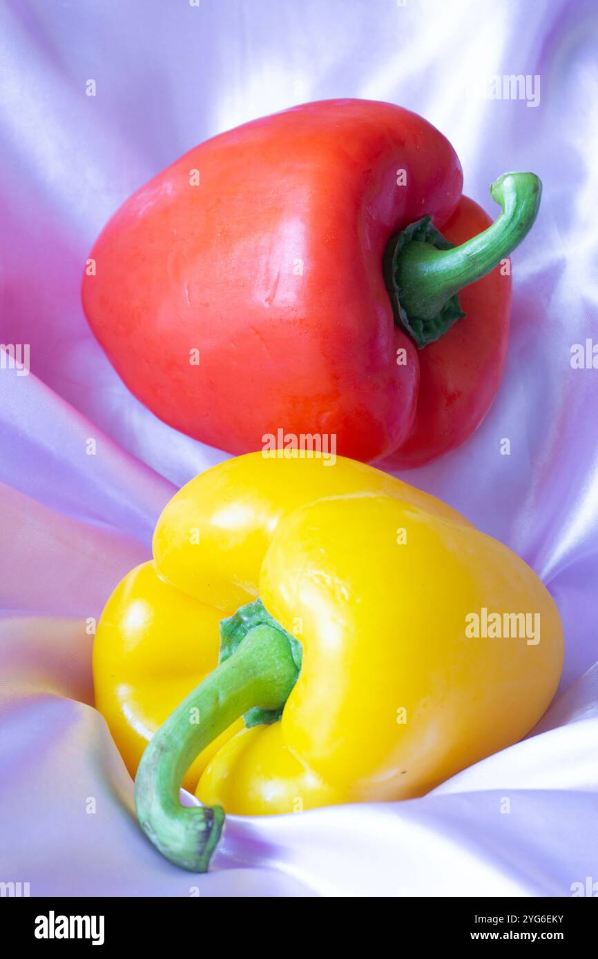 Peperone giallo su sfondo in tessuto satinato rosa chiaro - fotografia STILL Life - fotografia alimentare Foto Stock