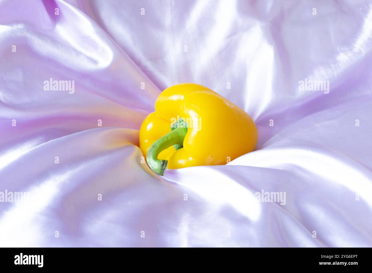 Peperone giallo su sfondo in tessuto satinato rosa chiaro - fotografia STILL Life - fotografia alimentare Foto Stock