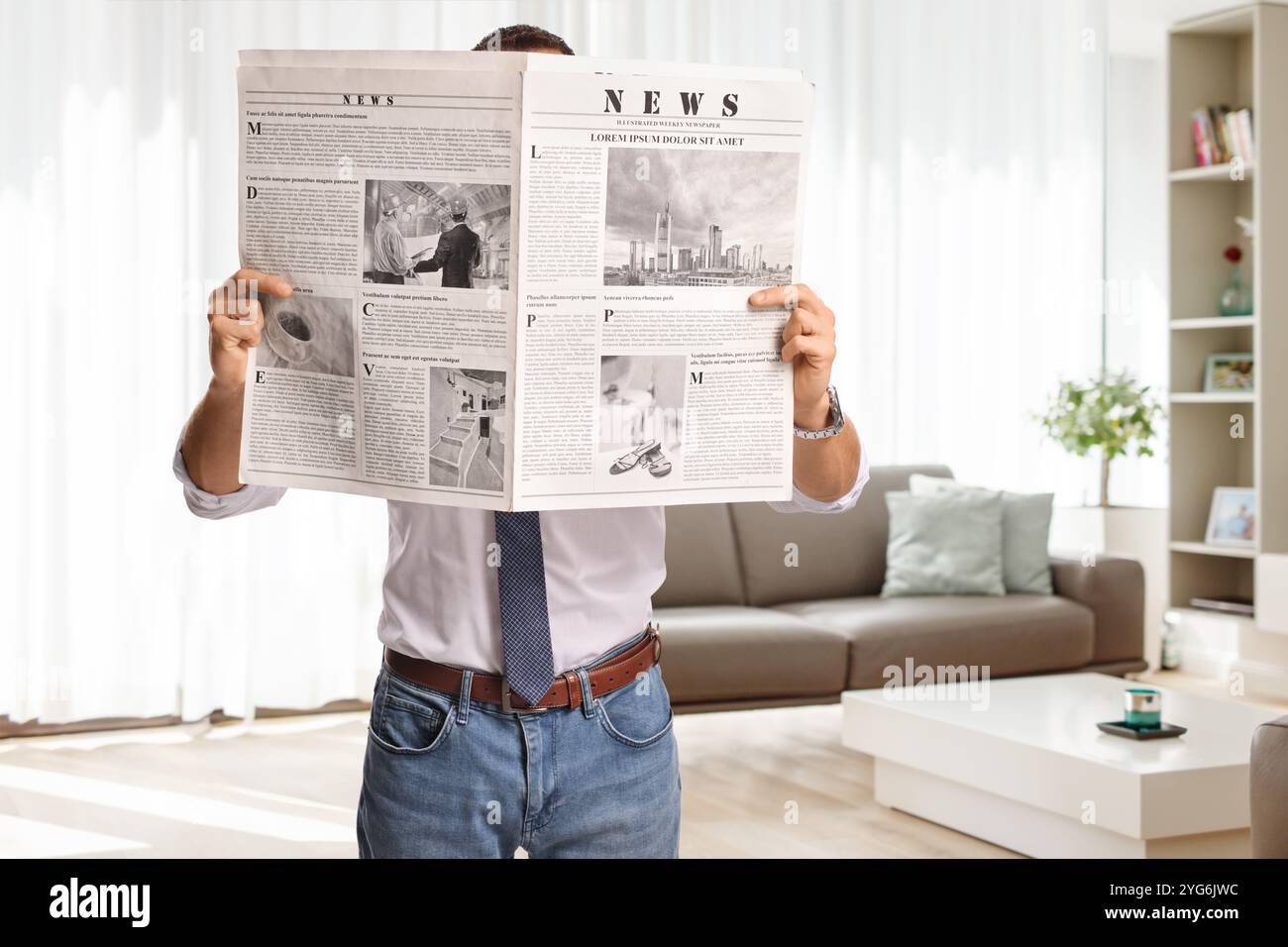 Uomo in piedi a leggere un giornale a casa in salotto Foto Stock
