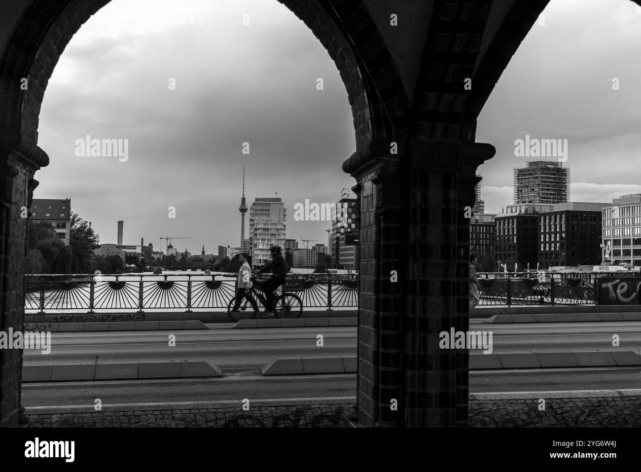 Vista in bianco e nero attraverso i pilastri del ponte Oberbaum (Oberbaumbrücke) e Sprea e sfondo urbano, Berlino, Germania, Europa Foto Stock
