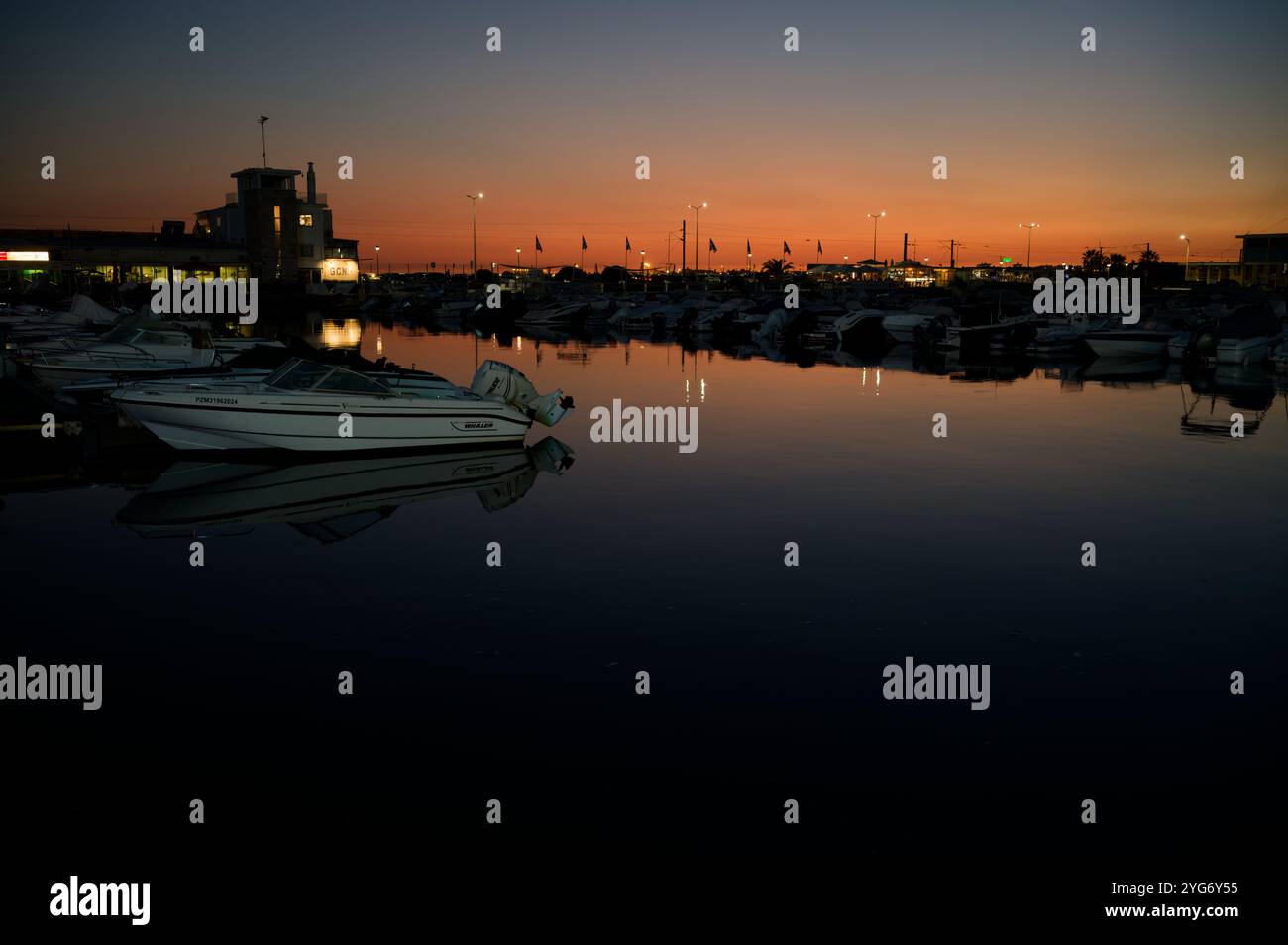 Tramonto sereno sul porto turistico di Faro, che proietta un caldo bagliore sulle barche ancorate e sulle acque calme Foto Stock