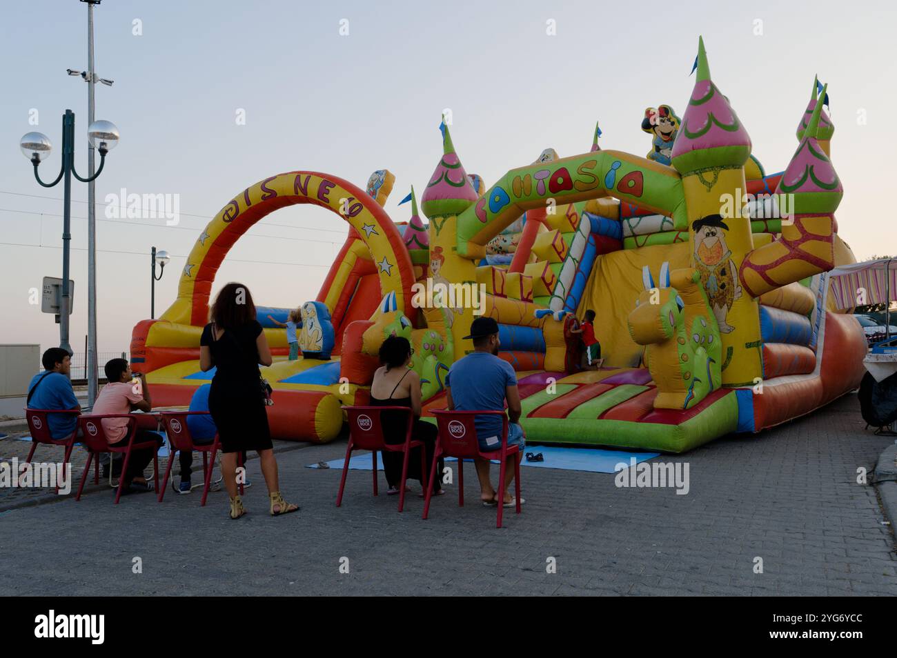 Parco giochi gonfiabile colorato con personaggi dei cartoni animati, intrattenere bambini e famiglie in una vivace fiera serale Foto Stock