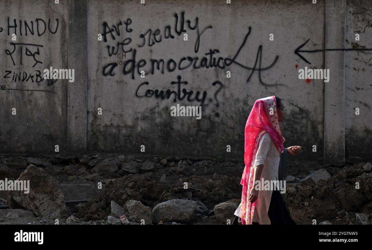 Mumbai, India. 6 novembre 2024. Una donna passa davanti a un graffite dipinto su un muro per le strade di Mumbai. I graffiti sono una forma visiva di comunicazione dipinta intorno allo spazio pubblico illegalmente o senza permesso. E' un commento su uno scenario sociale e politico dentro e intorno al paese. Credito: SOPA Images Limited/Alamy Live News Foto Stock
