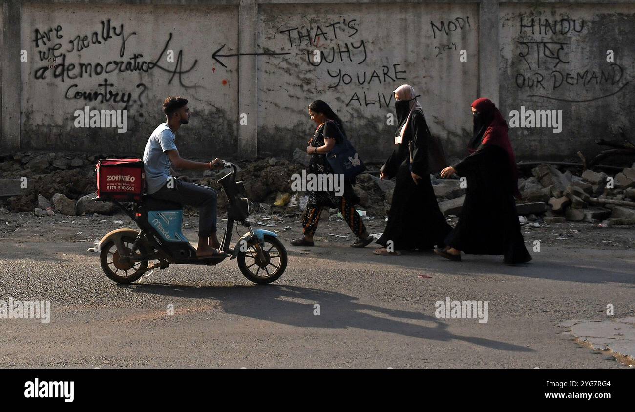 Mumbai, India. 6 novembre 2024. Si vedono persone che camminano davanti a graffiti dipinti su un muro nelle strade di Mumbai. I graffiti sono una forma visiva di comunicazione dipinta intorno allo spazio pubblico illegalmente o senza permesso. E' un commento su uno scenario sociale e politico dentro e intorno al paese. (Foto di Ashish Vaishnav/SOPA Images/Sipa USA) credito: SIPA USA/Alamy Live News Foto Stock