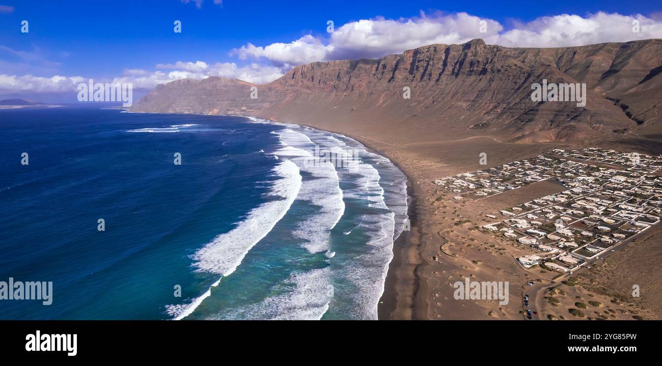 Caleta de Famara - splendida spiaggia dell'isola di Lanzarote populista per i surfisti. vista panoramica del drone aereo. Isole Canarie della Spagna Foto Stock