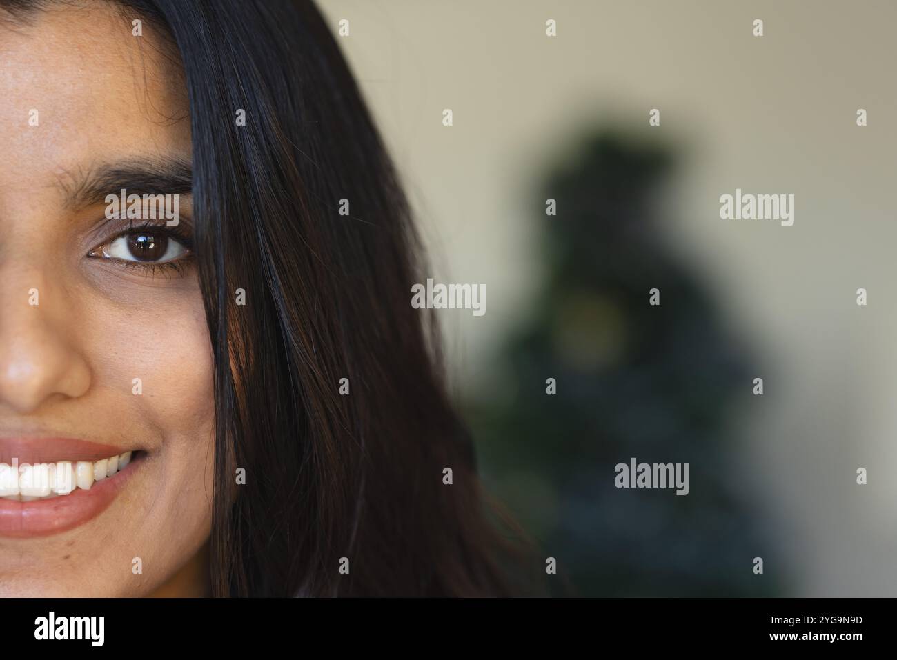 Donna asiatica sorridente che si gode la stagione delle feste con l'albero di Natale sullo sfondo, copia spazio Foto Stock