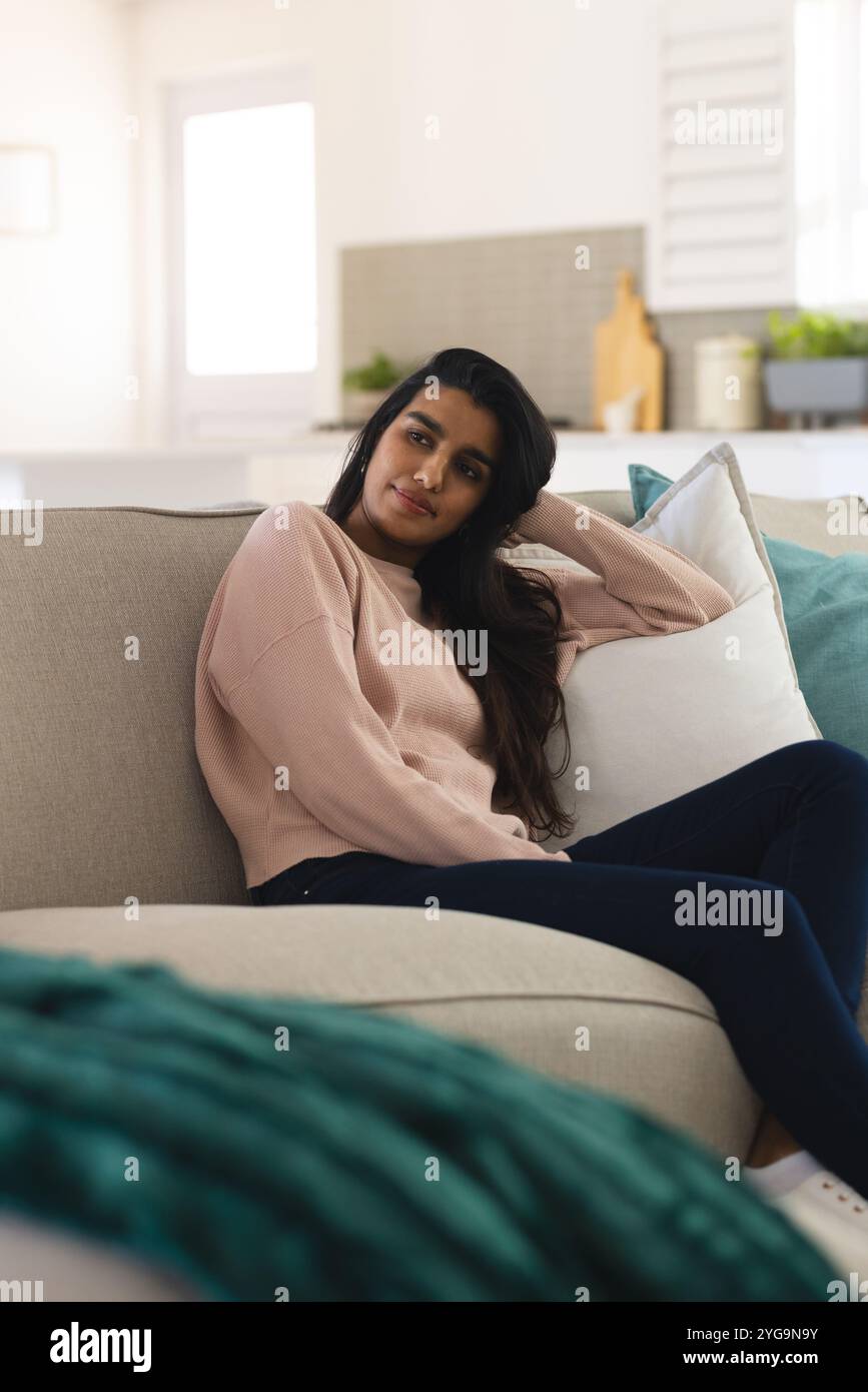 Rilassatevi sul divano, giovane donna che sogna a casa con un comodo maglione Foto Stock