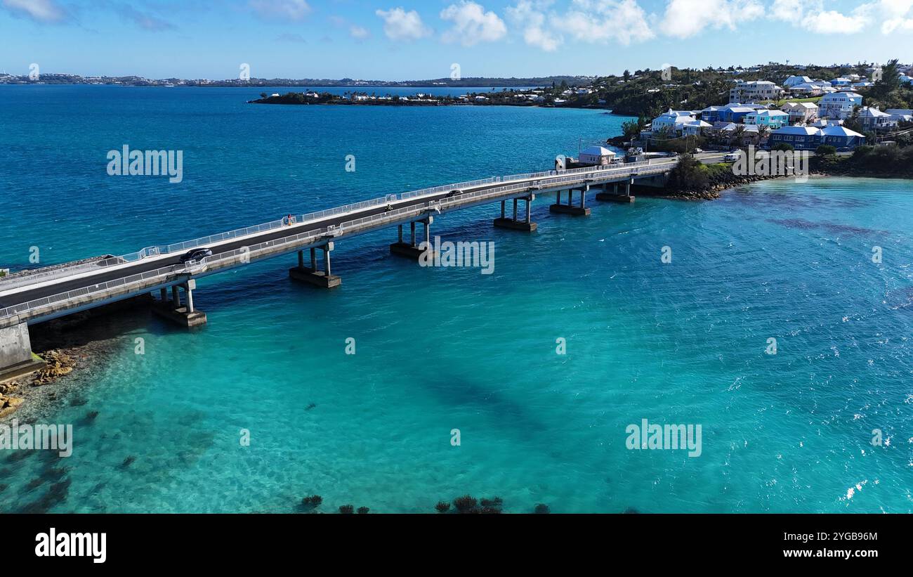 Un dinamico drone che cattura Waterford Bridge attraverso le splendide acque bermudane, creando schizzi e sentieri nel mare turchese cristallino Foto Stock