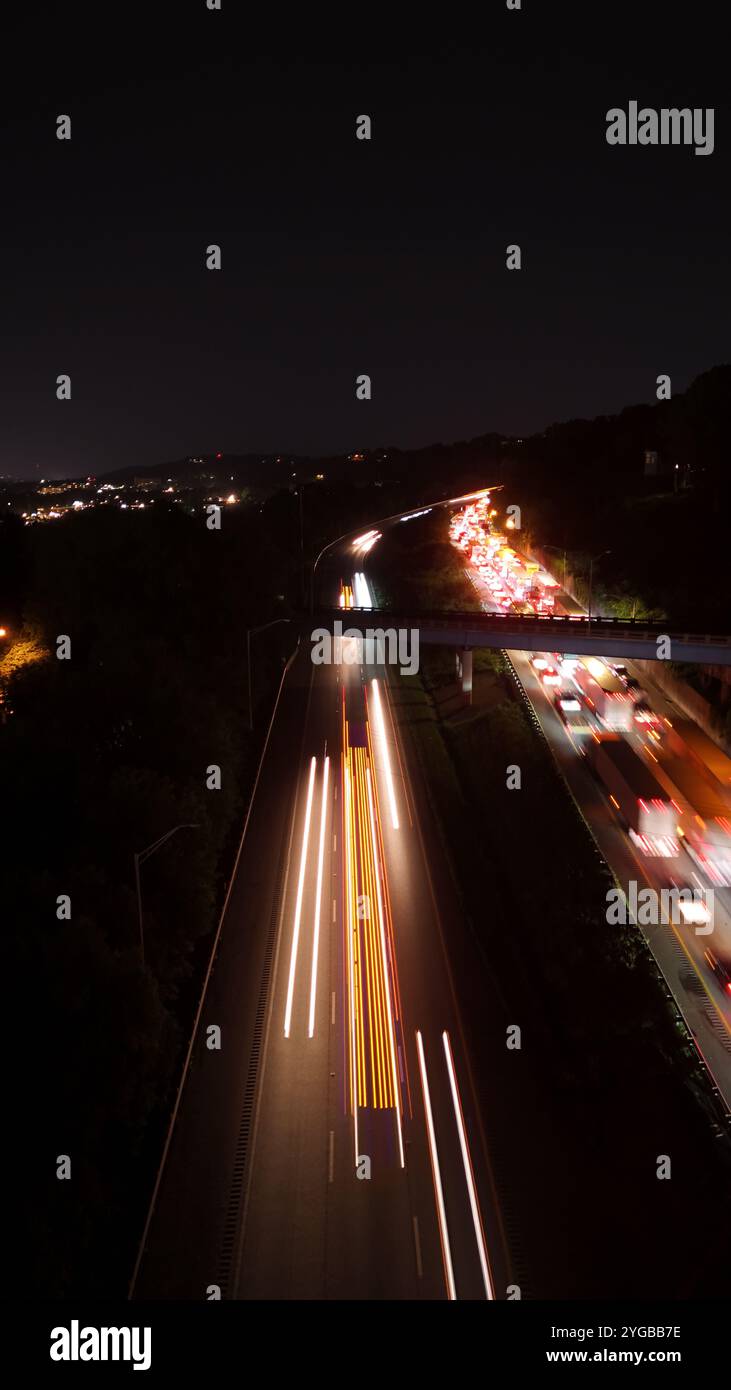 Gli scatti notturni a lunga esposizione del paesaggio urbano catturano vivaci percorsi di luce dalle auto di passaggio e dalle strade illuminate. Foto Stock