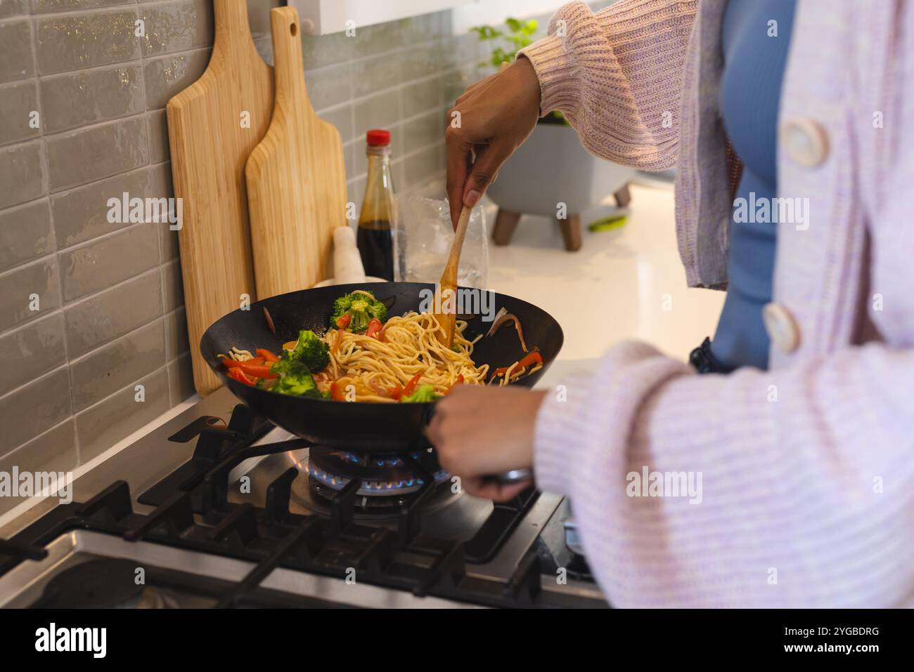 Cuocere spaghetti in padella con verdure sul piano cottura in un'accogliente cucina, a casa Foto Stock