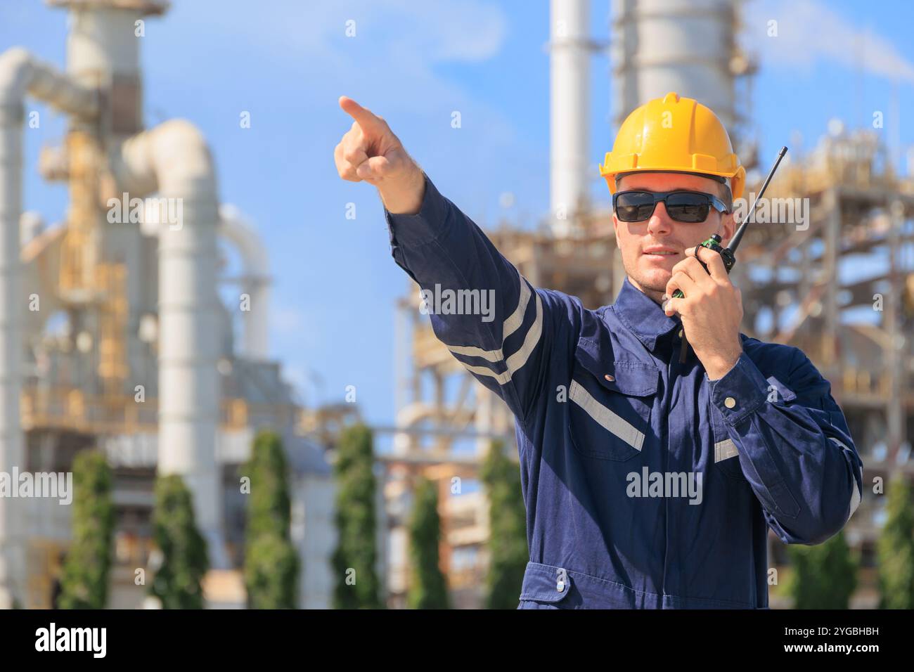 Ingegnere del settore petrolifero che lavora all'aperto. Il controllo del team di assistenza per petrolio e gas degli impianti di raffineria gestisce la parte anteriore di manutenzione di grandi tubazioni di gas complesse Foto Stock