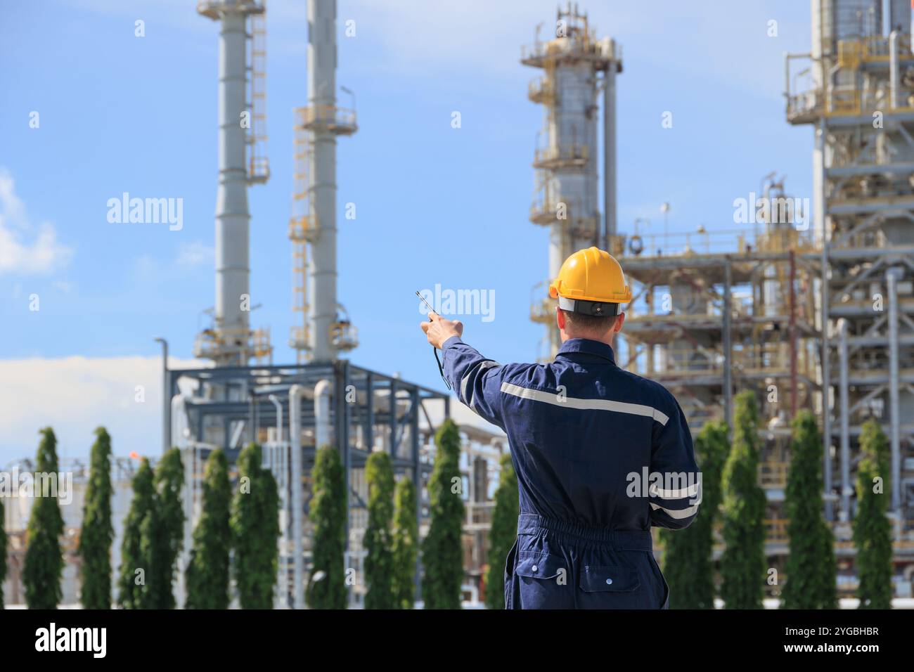 Operaio del petrolio della raffineria in servizio con radiocomando. Ingegnere industriale nel settore del petrolio e del gas che lavora in impianti petrolchimici. Foto Stock