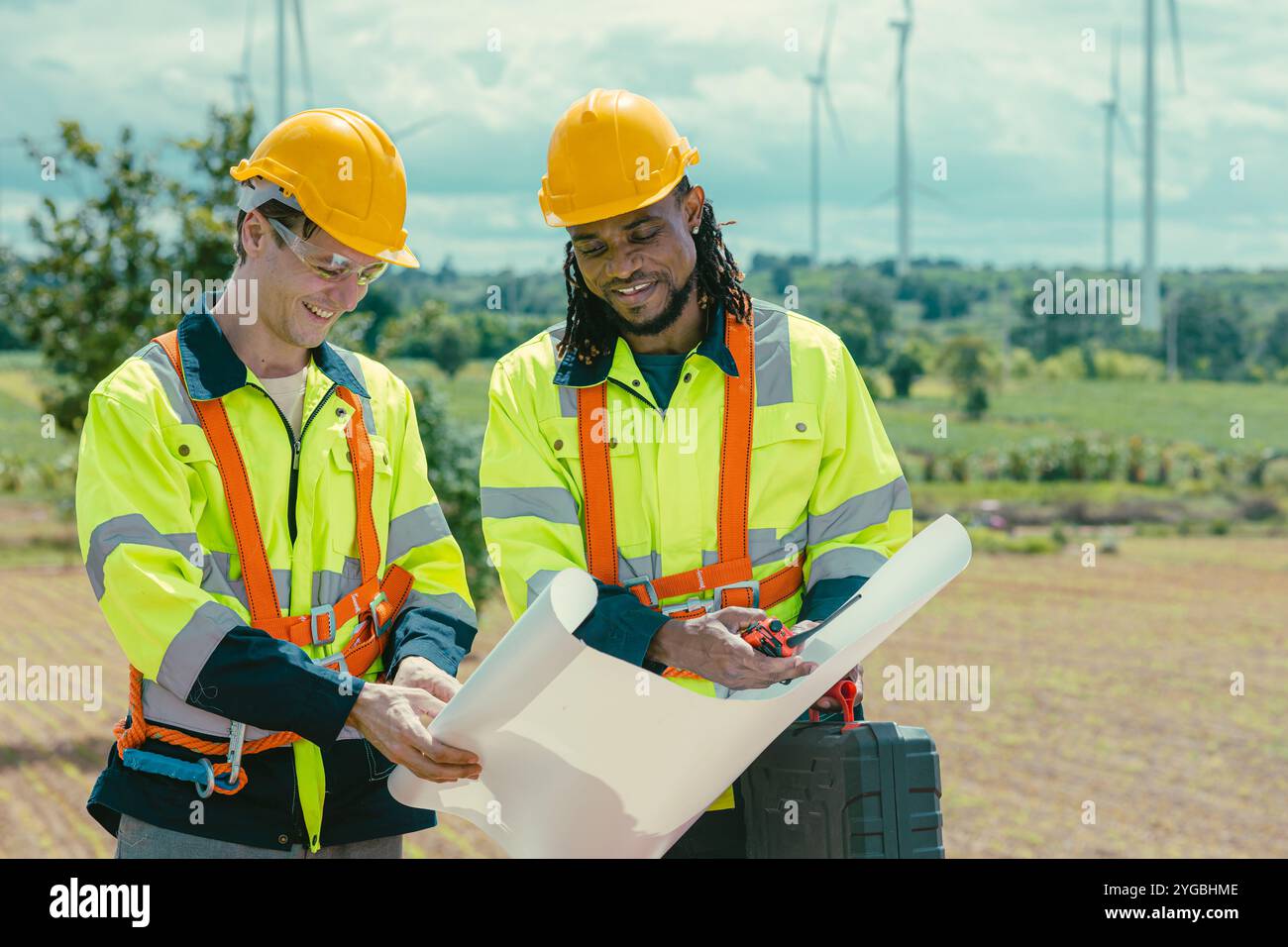 Il team di ingegneri mescola lavoratori maschi in bianco e nero con la planimetria del sondaggio sul lavoro sul campo di Wind Turbines presso il campo agricolo di generatori di energia eolica all'aperto. Foto Stock Il team di ingegneri mescola lavoratori maschi in bianco e nero con la planimetria del sondaggio sul lavoro sul campo di Wind Turbines presso il campo agricolo di generatori di energia eolica all'aperto. Foto Stock