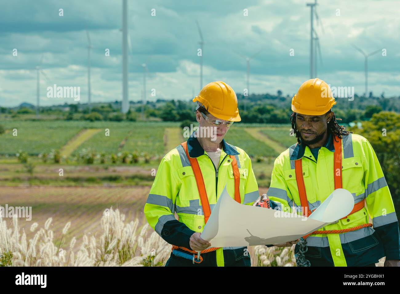 Il team di ingegneri mescola lavoratori maschi in bianco e nero con la planimetria del sondaggio sul lavoro sul campo di Wind Turbines presso il campo agricolo di generatori di energia eolica all'aperto. Foto Stock Il team di ingegneri mescola lavoratori maschi in bianco e nero con la planimetria del sondaggio sul lavoro sul campo di Wind Turbines presso il campo agricolo di generatori di energia eolica all'aperto. Foto Stock