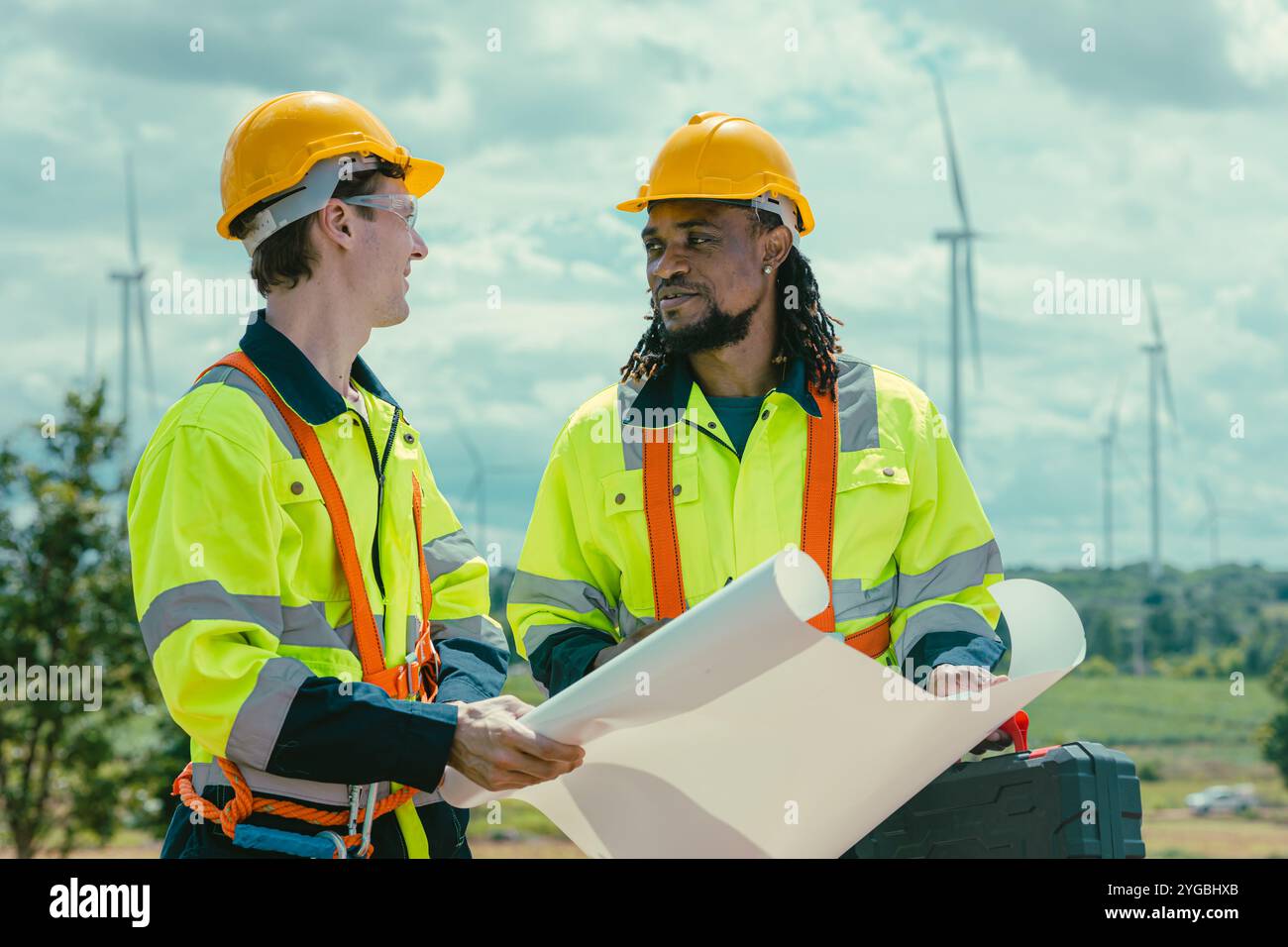 Il team di ingegneri mescola lavoratori maschi in bianco e nero con la planimetria del sondaggio sul lavoro sul campo di Wind Turbines presso il campo agricolo di generatori di energia eolica all'aperto. Foto Stock Il team di ingegneri mescola lavoratori maschi in bianco e nero con la planimetria del sondaggio sul lavoro sul campo di Wind Turbines presso il campo agricolo di generatori di energia eolica all'aperto. Foto Stock