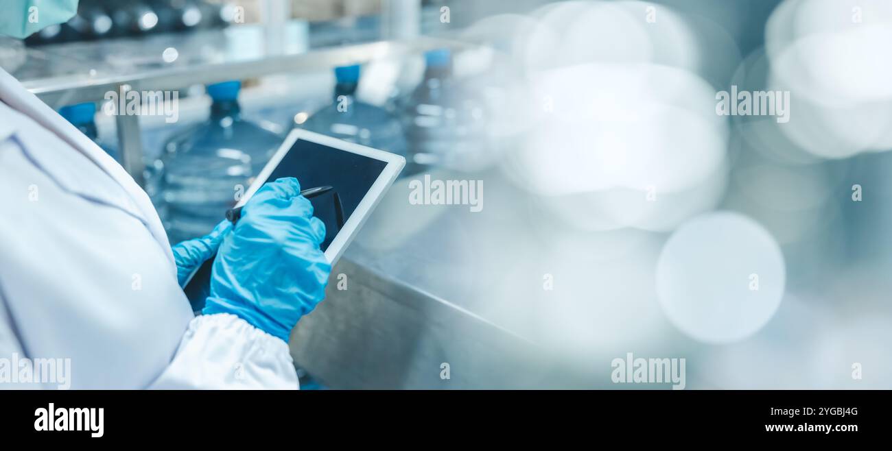 I lavoratori addetti all'igiene in primo piano lavorano con la tecnologia di gestione del software per tablet per gestire la produzione in una fabbrica moderna con spazio per il testo Foto Stock