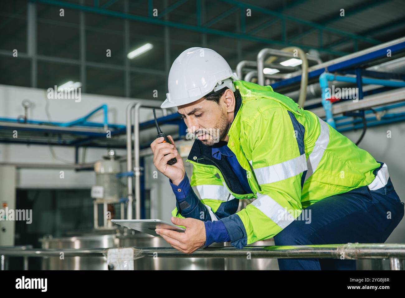 Ingegnere in servizio, lavoratore latino maschio in fabbrica in una centrale elettrica a gas e petrolio con controllo, gestisce l'ordine con comunicazione walkie-talkie al lavoro Foto Stock