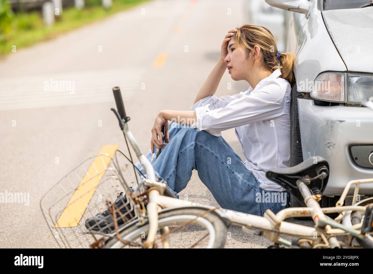 Le donne che guidano l'auto seduto si sentono in colpa davanti alla strada in attesa della polizia dopo che l'incidente ha colpito il ciclista in autostrada Foto Stock