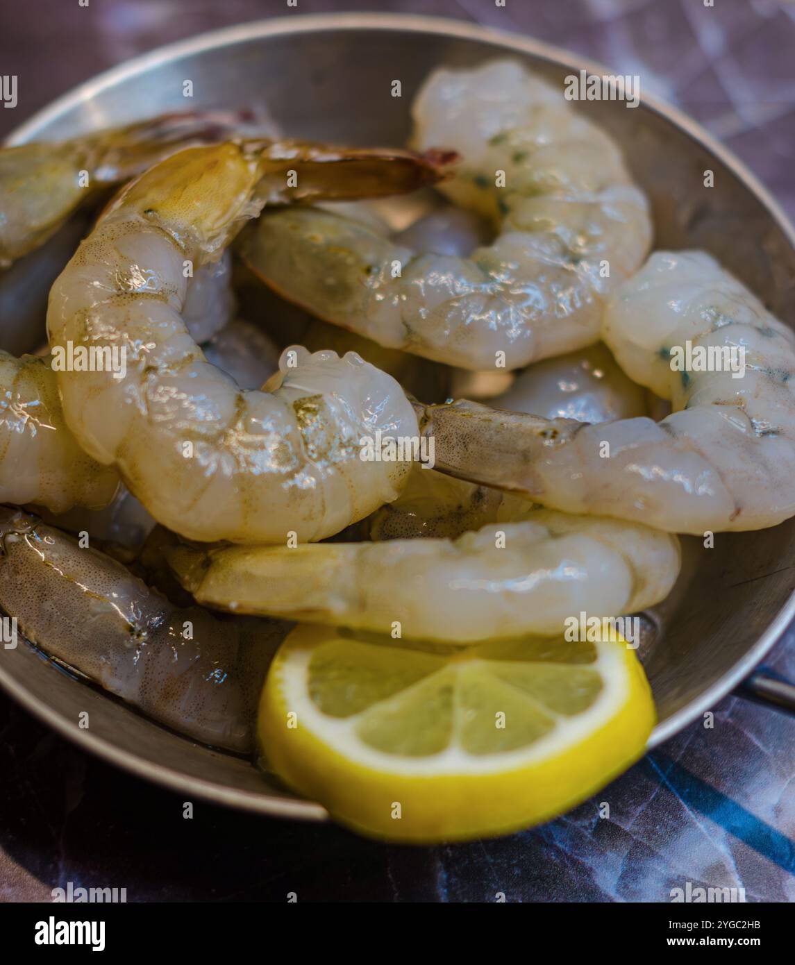 gamberi crudi, gamberi e fetta di limone su padella su sfondo grigio . Foto di alta qualità Foto Stock