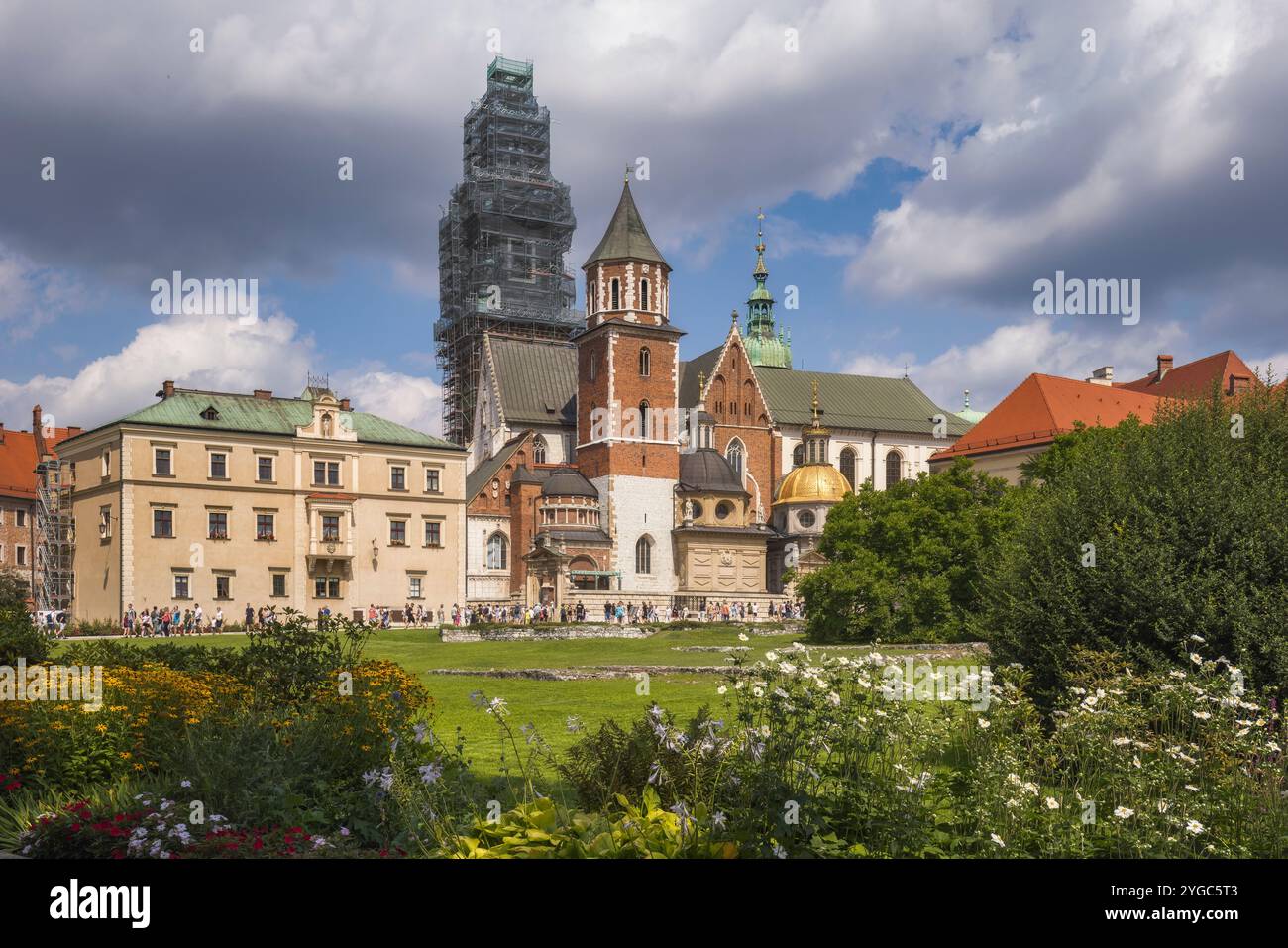 Esplora la splendida architettura del castello di Cracovia circondato da giardini lussureggianti sotto un cielo luminoso, la Polonia Foto Stock