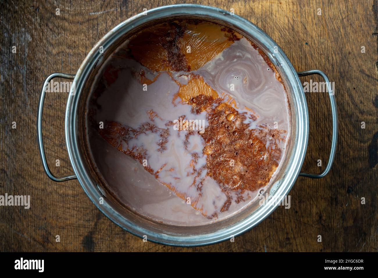 Bevanda al cacao appena preparata in una padella metallica su un tavolo di legno, vista ravvicinata dall'alto Foto Stock