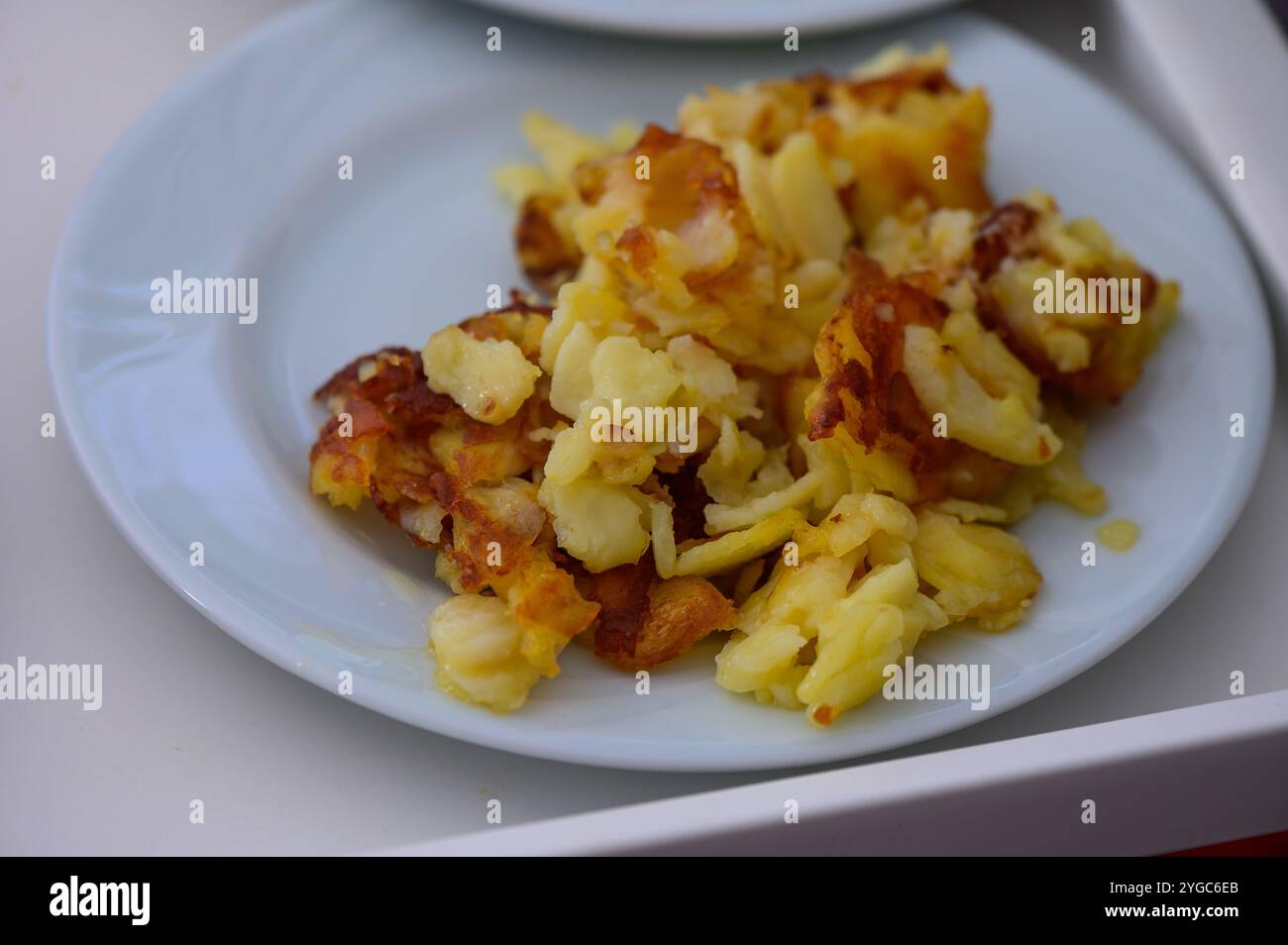 I pancake dorati e croccanti di patate sono serviti su un piatto blu chiaro, invitando gli appetiti ad un incontro allegro. Foto Stock