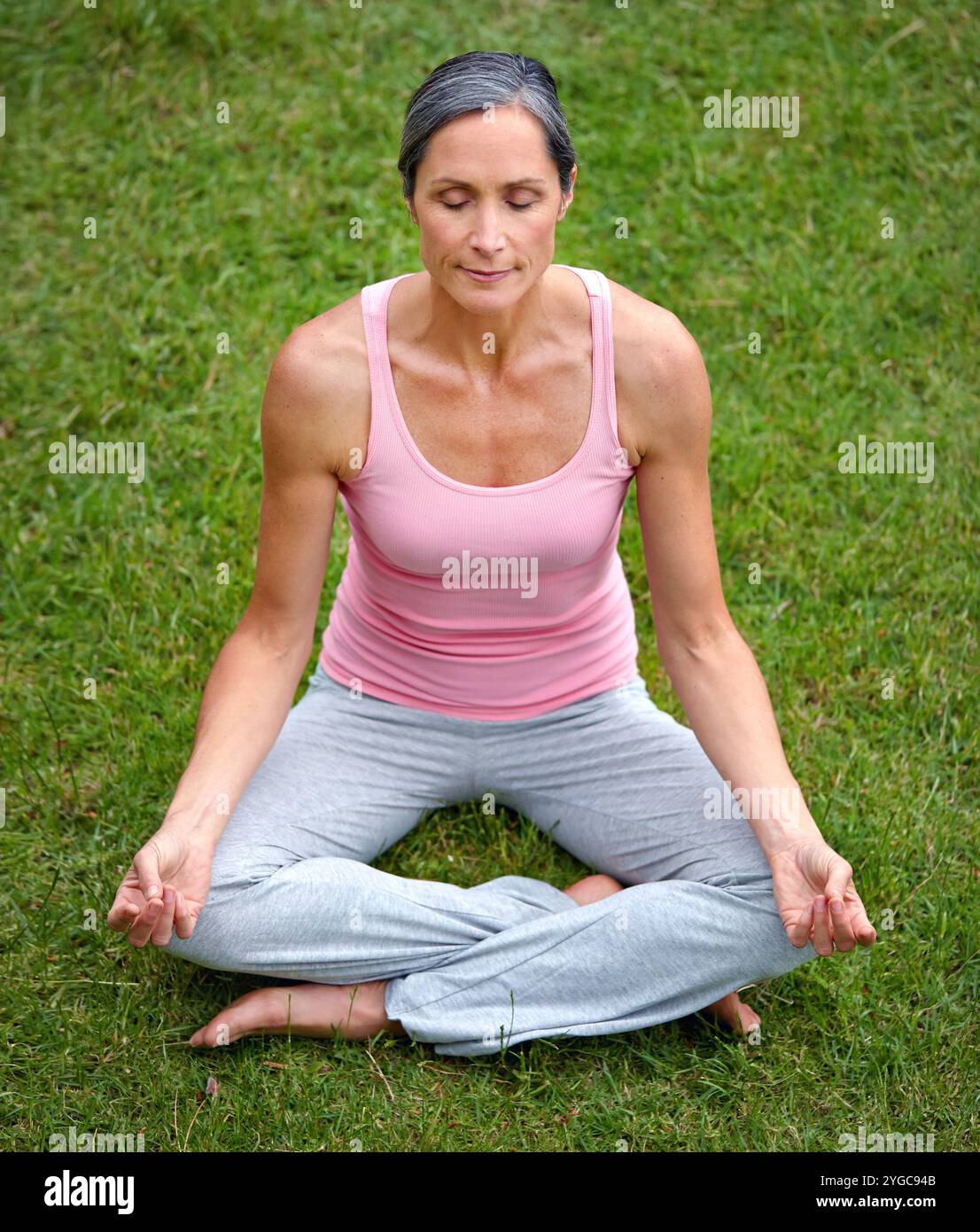 Donna, all'aperto e loto in yoga per meditazione, pace o benessere in giardino. Persona fisica matura, zen o corpo sano su erba per spirituale Foto Stock