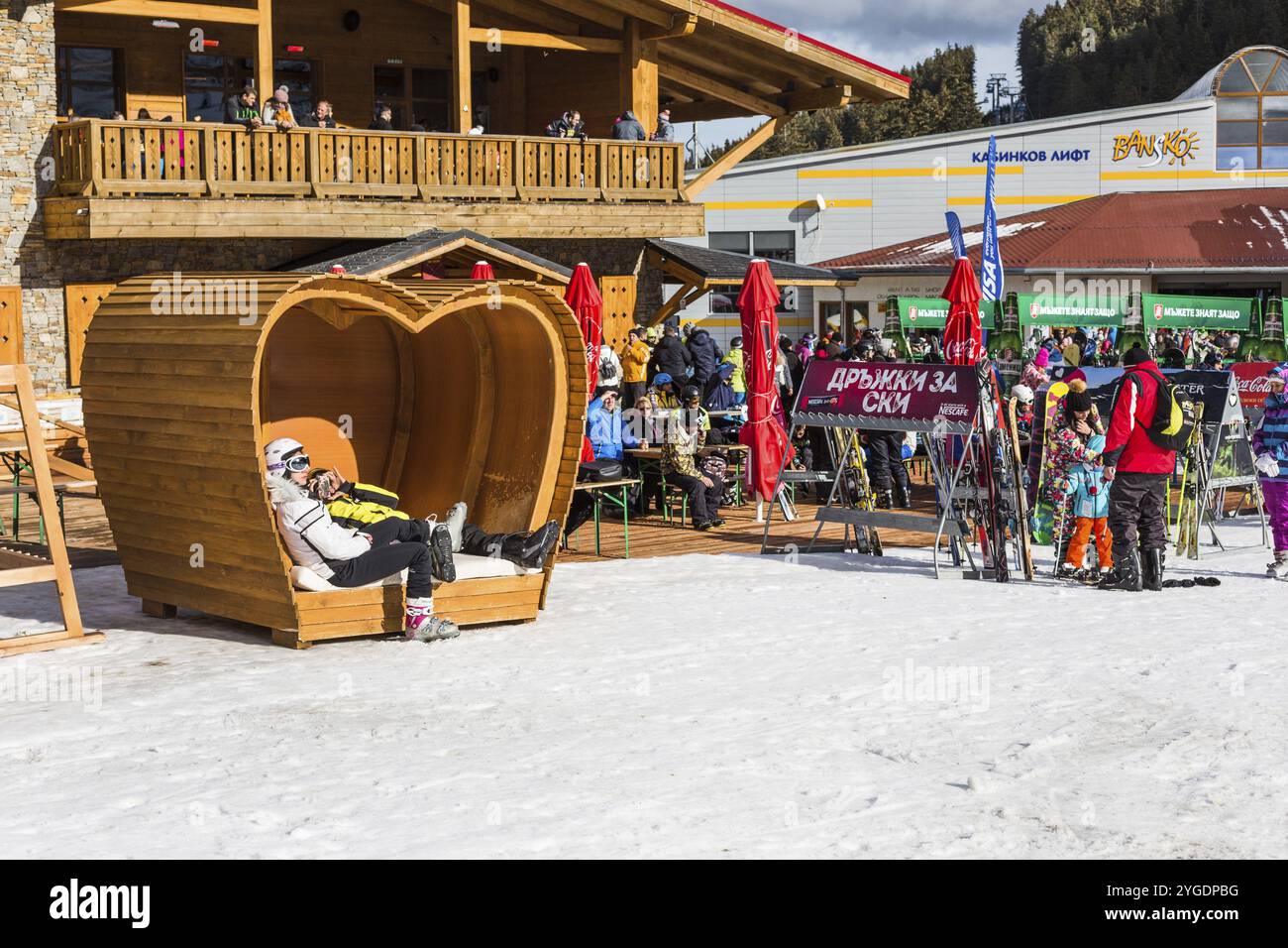 Bansko, Bulgaria, 12 dicembre 2015: Stazione sciistica bulgara, panchina a forma di cuore, gente che cammina e scia, Europa Foto Stock