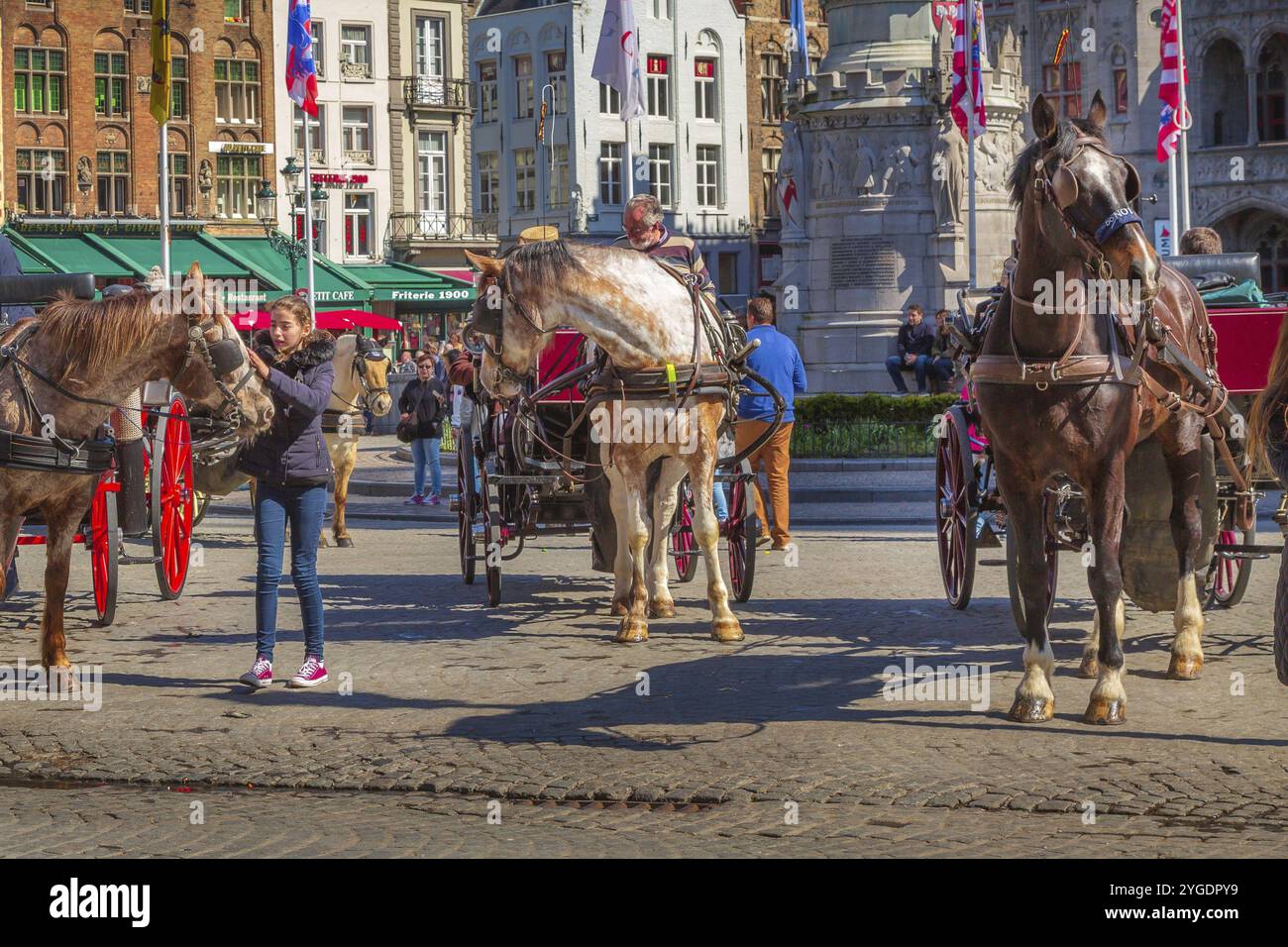 Bruges, Belgio, 10 aprile 2016: Carrozza trainata da cavalli sulla piazza del mercato nella popolare destinazione belga Bruges, Europa Foto Stock
