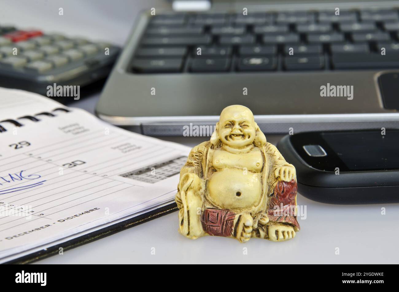 Statua di Buddha davanti all'attrezzatura da ufficio che simboleggia la riduzione dello stress Foto Stock