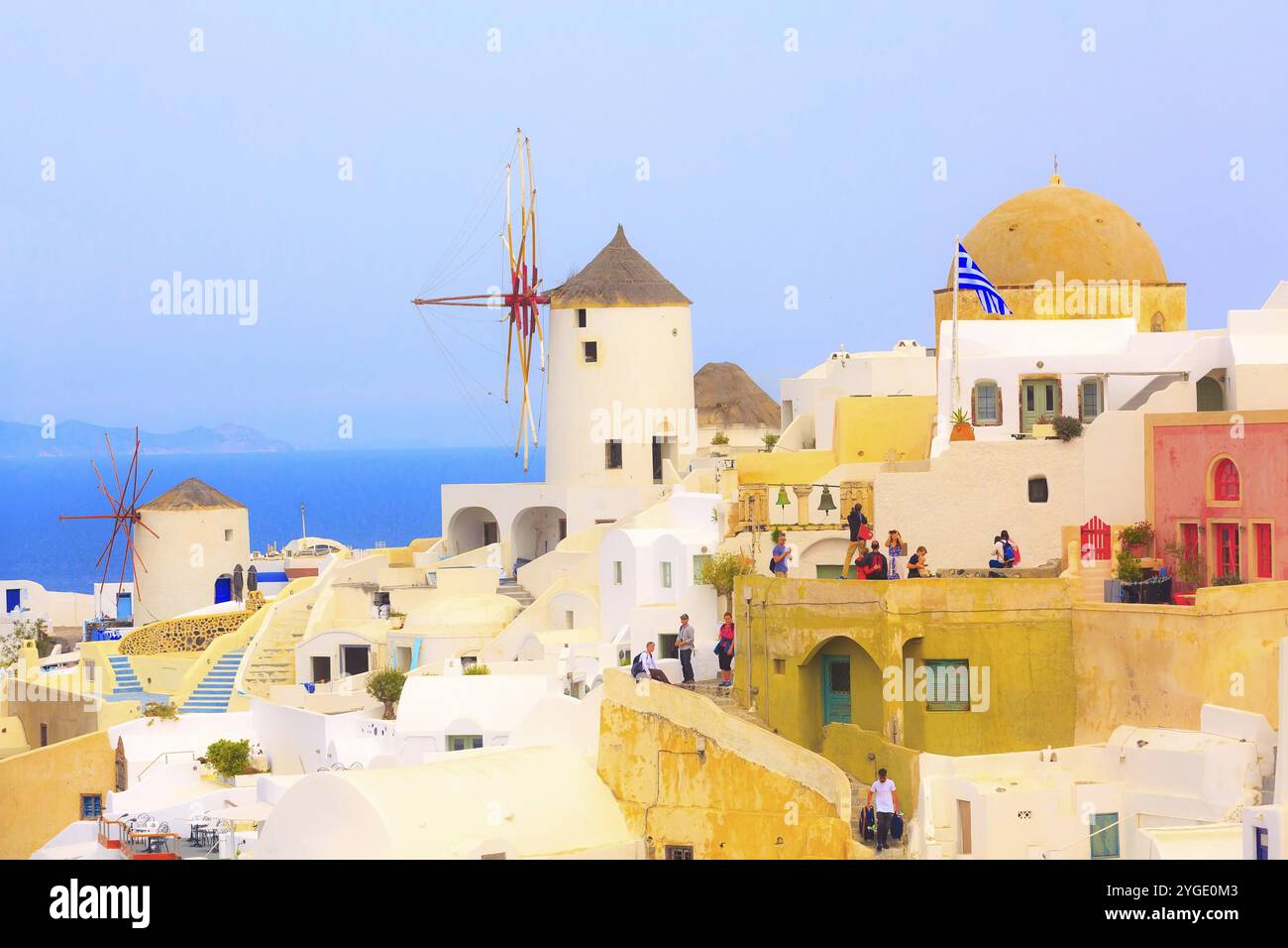 Oia, Santorini, Grecia, 25 aprile 2019: Mulino a vento, mare blu e case colorate con bandiera greca, Europa Foto Stock