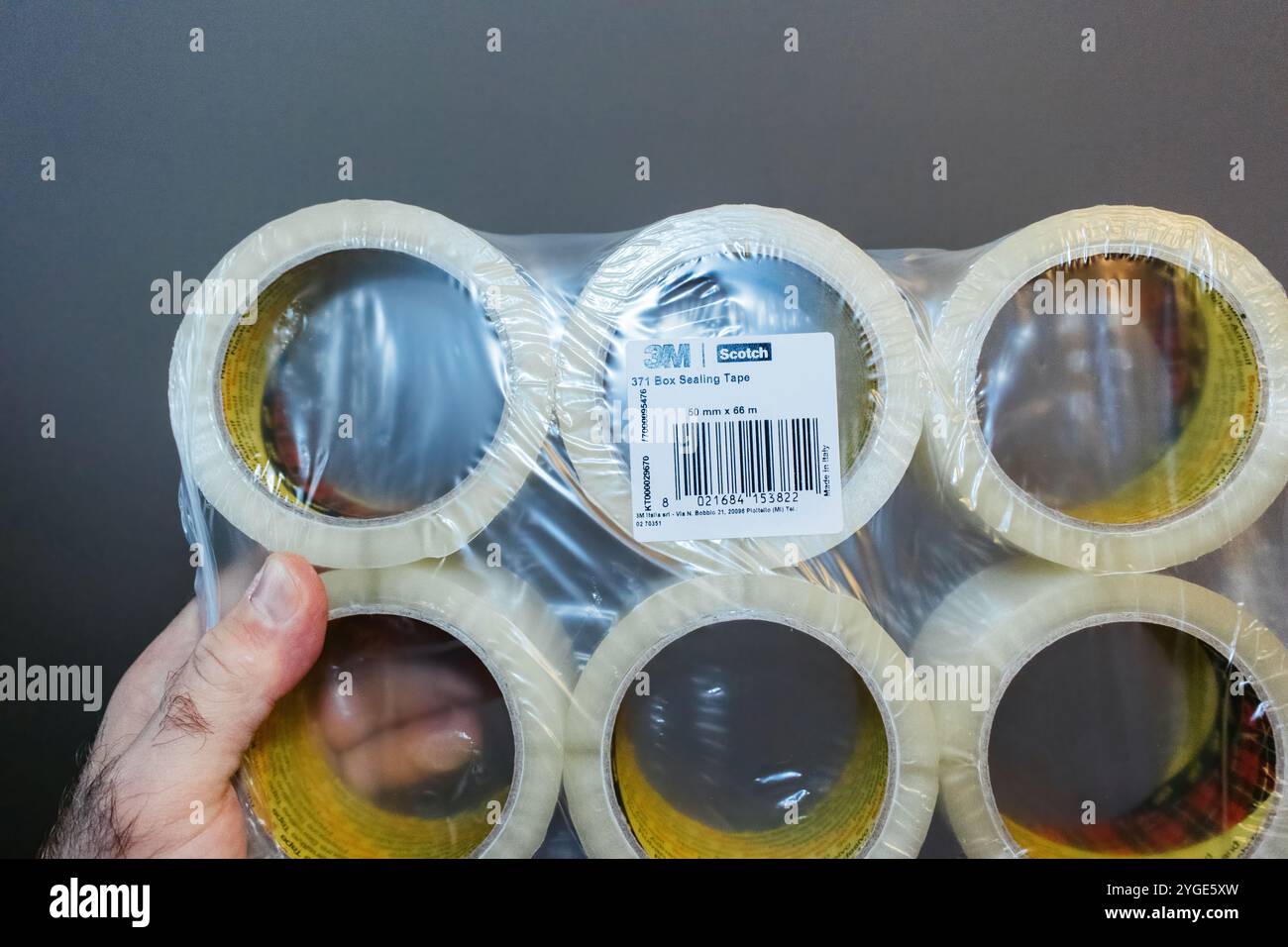 Parigi, Francia - 6 novembre 2024: Una mano può contenere una confezione da sei di nastro sigillante 3M Scotch Box, 50 mm x 66 m, avvolto in plastica, con dettagli sull'imballaggio e sull'etichetta Foto Stock