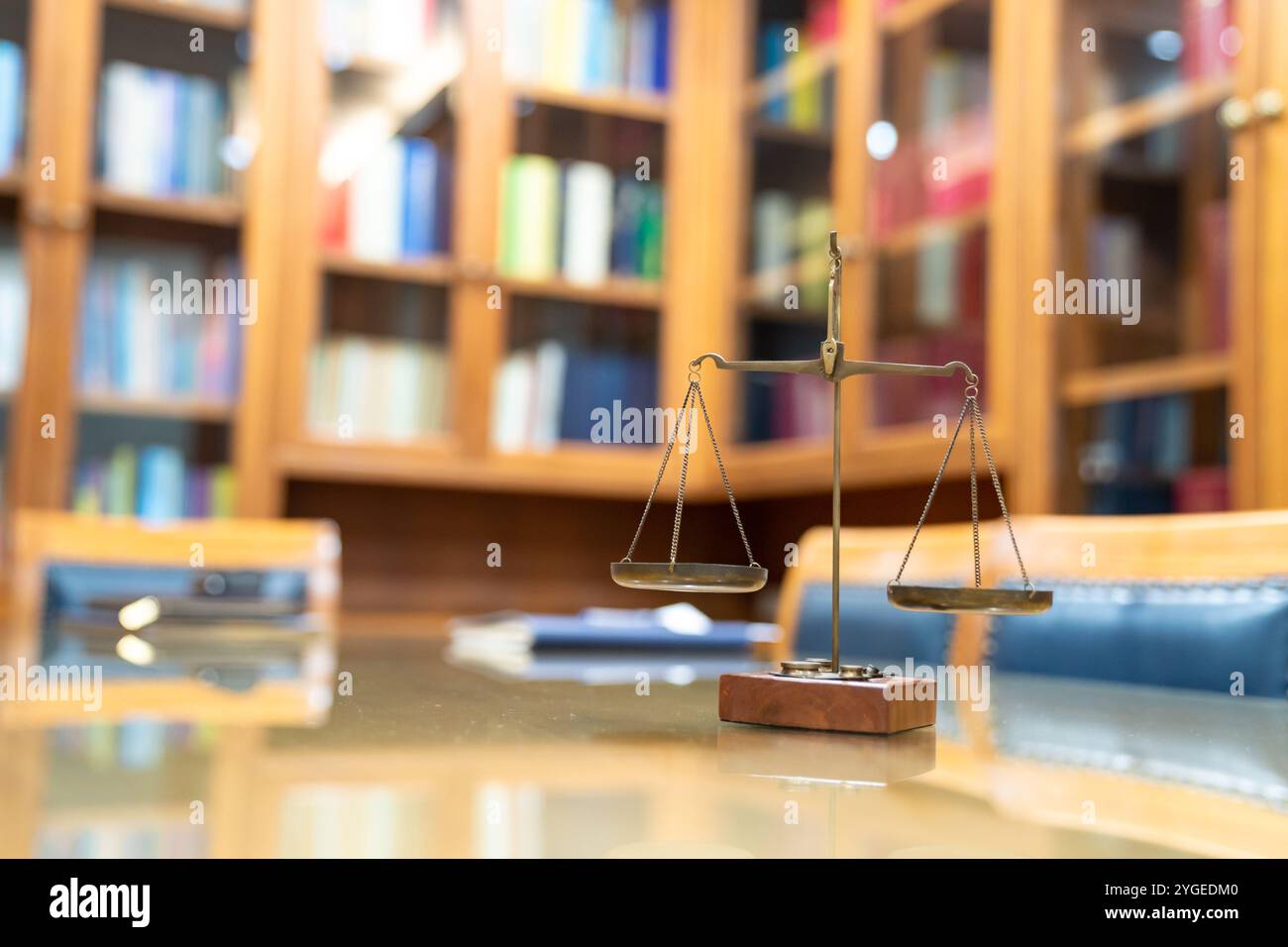 La vecchia scala di legge di Ottone è in stile vintage su un tavolo di vetro di legno nella sala riunioni dell'ufficio di Lawyer. Foto Stock