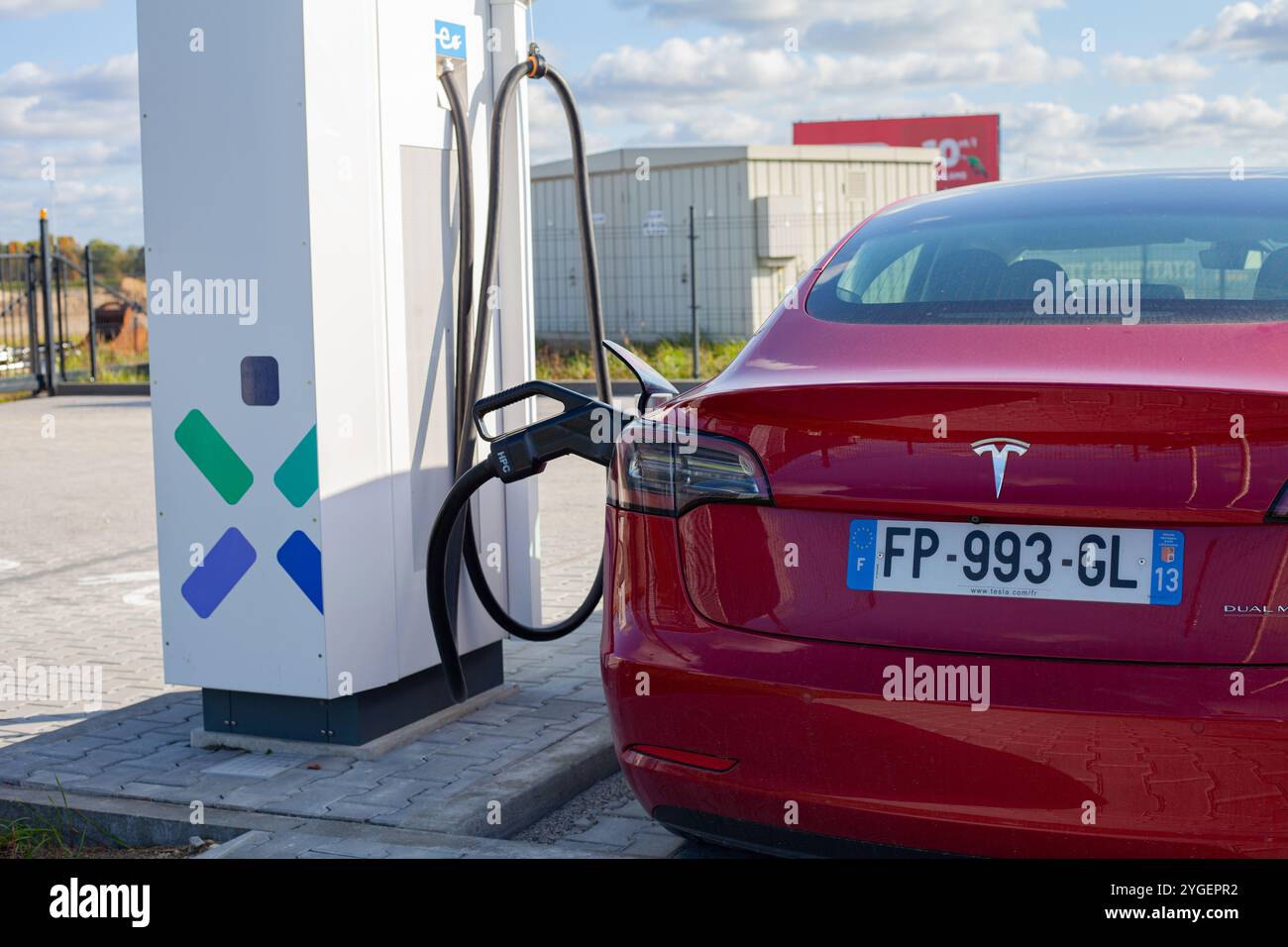 Auto americana elettrica rossa Tesla Model 3 Dual Motor nel parcheggio con stazione di ricarica rapida Foto Stock