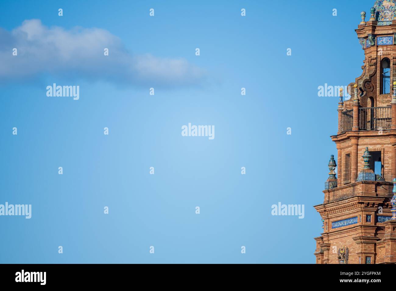 La torre architettonica dettagliata di Plaza de España a Siviglia, in Spagna, si affaccia su un cielo blu vibrante con una nuvola isolata. Un bell'esempio di spani Foto Stock