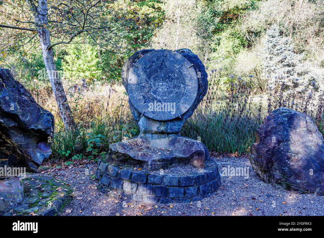 Replica di un calendario azteco scolpito nella roccia tra due pietre, vegetazione arida illuminata dal sole sullo sfondo, soleggiata giornata autunnale nel Willy-Dohmen Park, Ubach-P. Foto Stock
