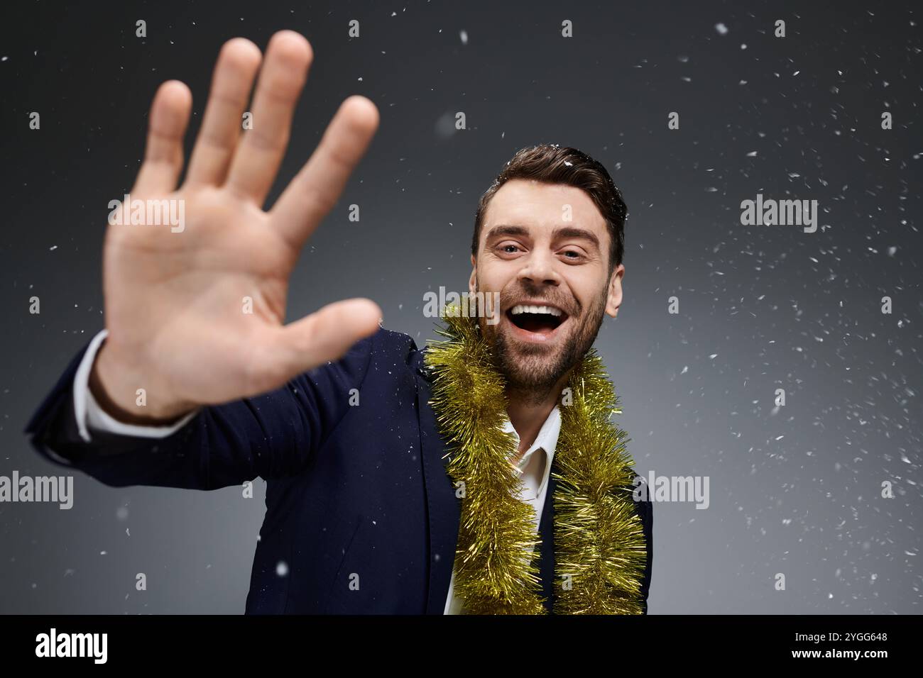 Un bel giovane con grandi onde sorridenti mentre adornato in una festa garland. Foto Stock