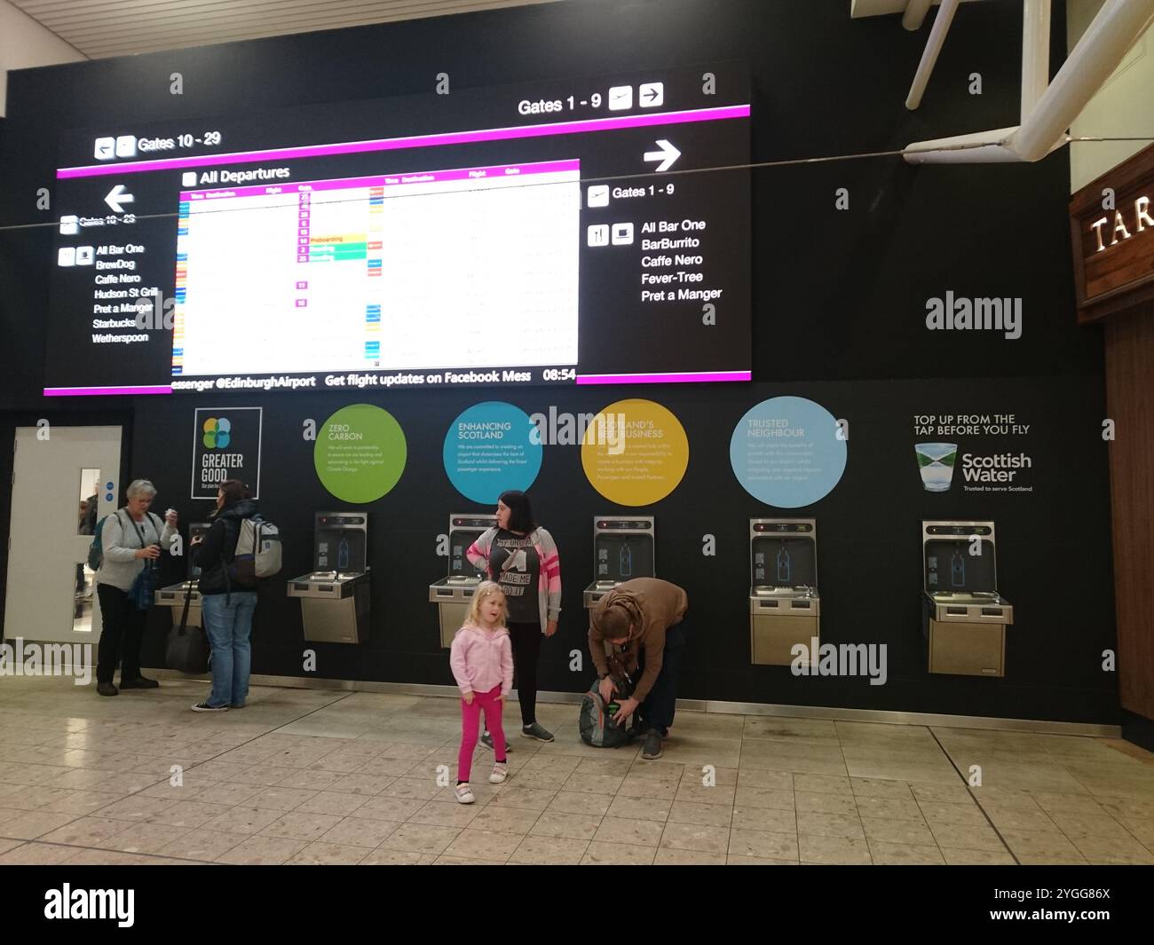 Ricarica dell'aeroporto di Edimburgo: Tocca sotto il Gate Information Board Foto Stock
