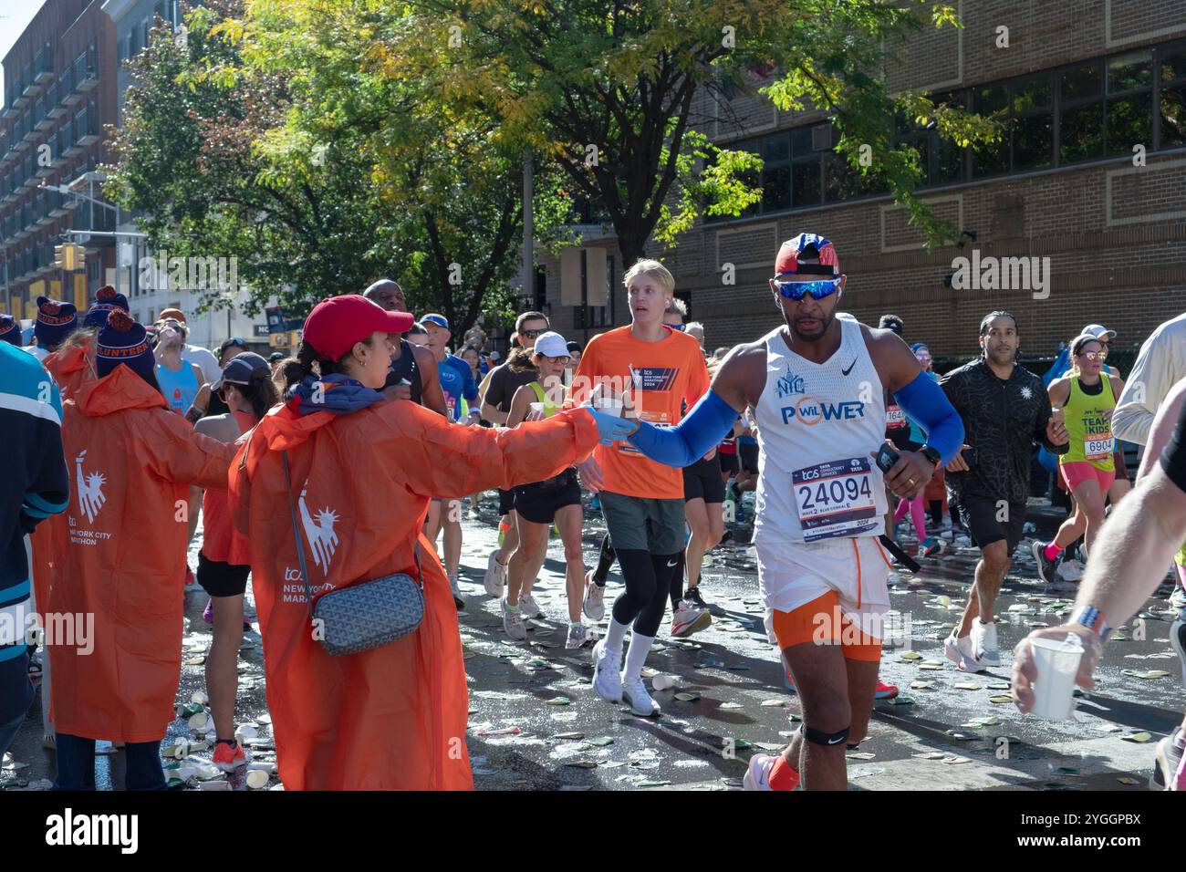 Ai 16 km della maratona di New York del 2024, i volontari mantengono i corridori idratati con bicchieri d'acqua. Su Bedford Avenue a Williamsburg, Brooklyn, N. Foto Stock